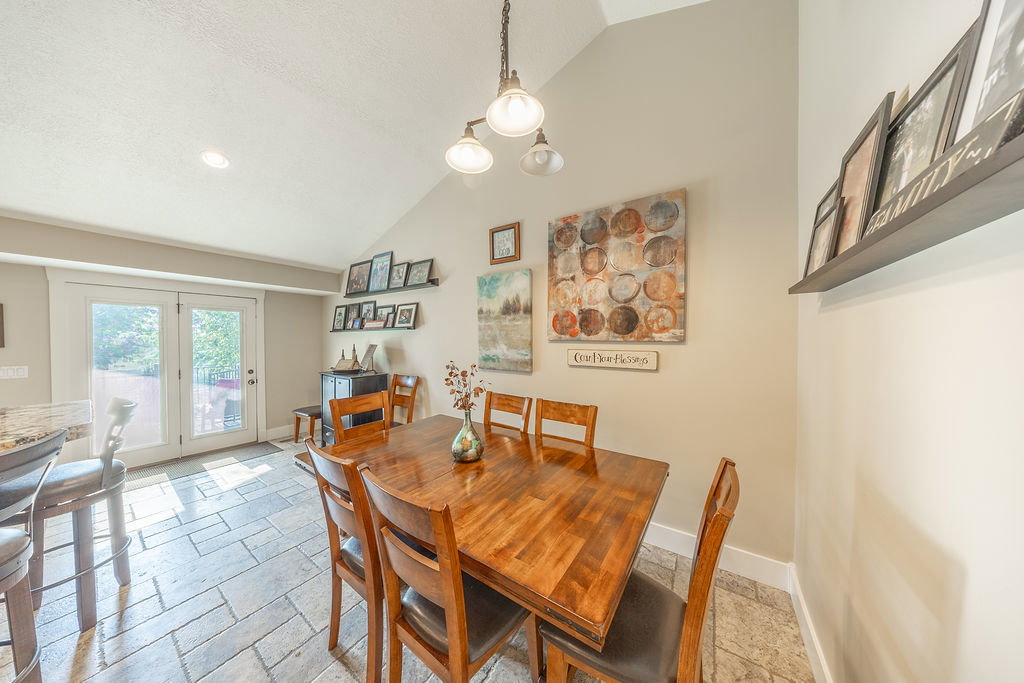 Vaulted ceiling dining area featuring tile flooring, white double French doors, and recessed lighting