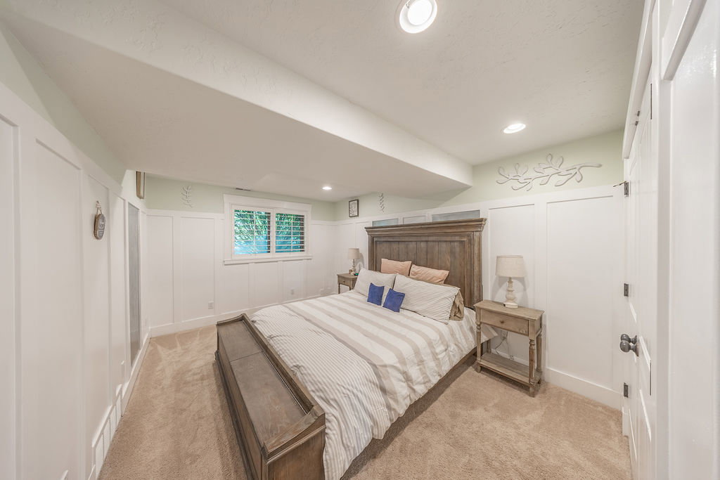Bedroom featuring board and batten wainscoting, recessed lighting, and a window with plantation shutters