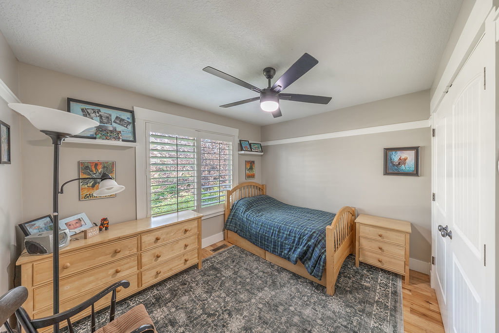 Interior space featuring a ceiling fan with integrated lighting, a window with plantation shutters, light-toned wall paint, white trim, and hardwood flooring