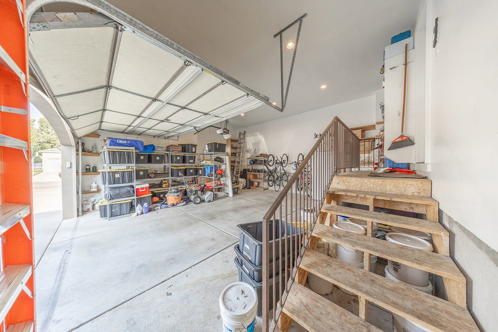 Attached two-car garage with a concrete floor, overhead lighting, and built-in shelving