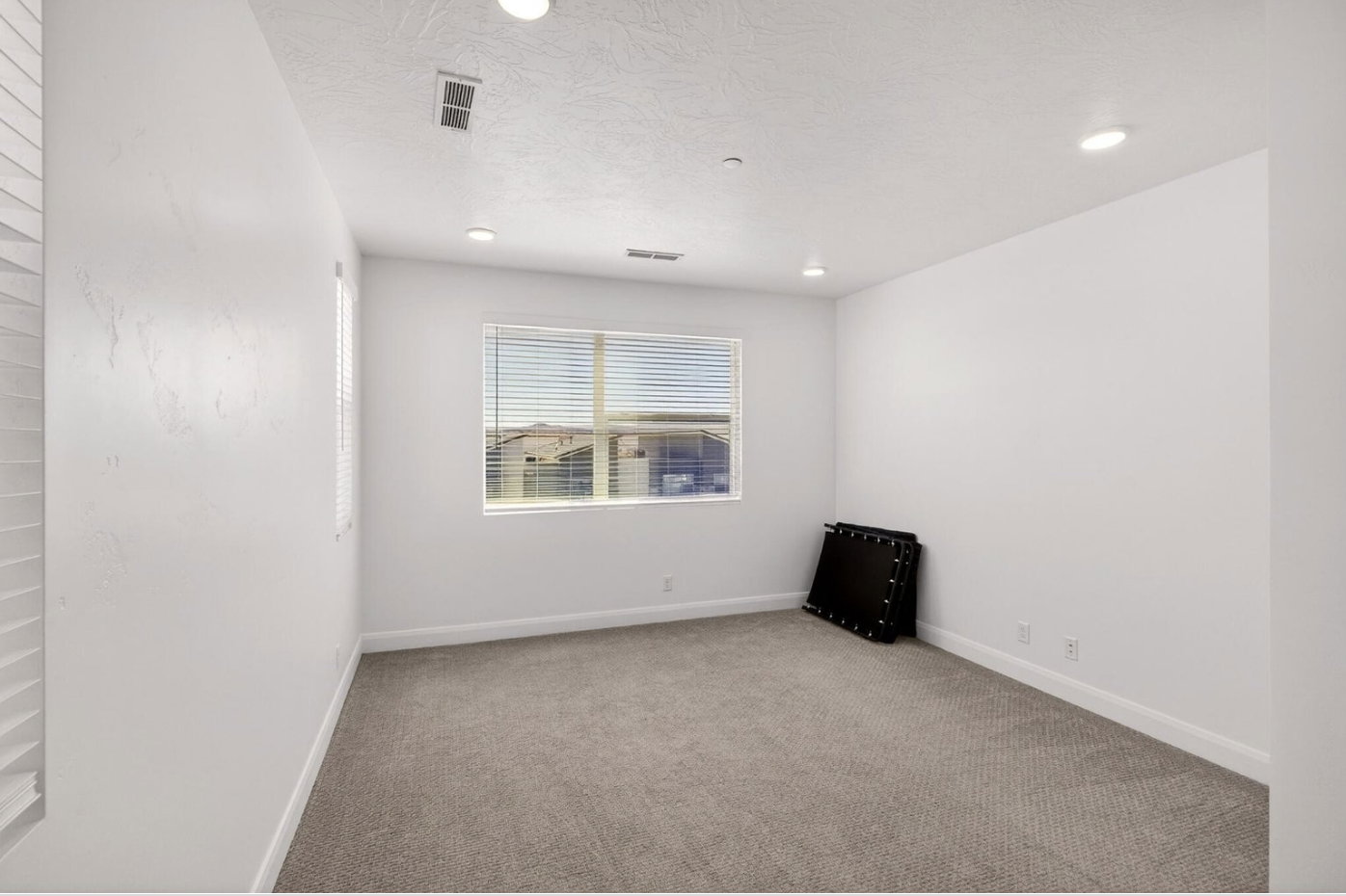Carpeted room featuring a large window with horizontal blinds, recessed lighting, and white baseboards