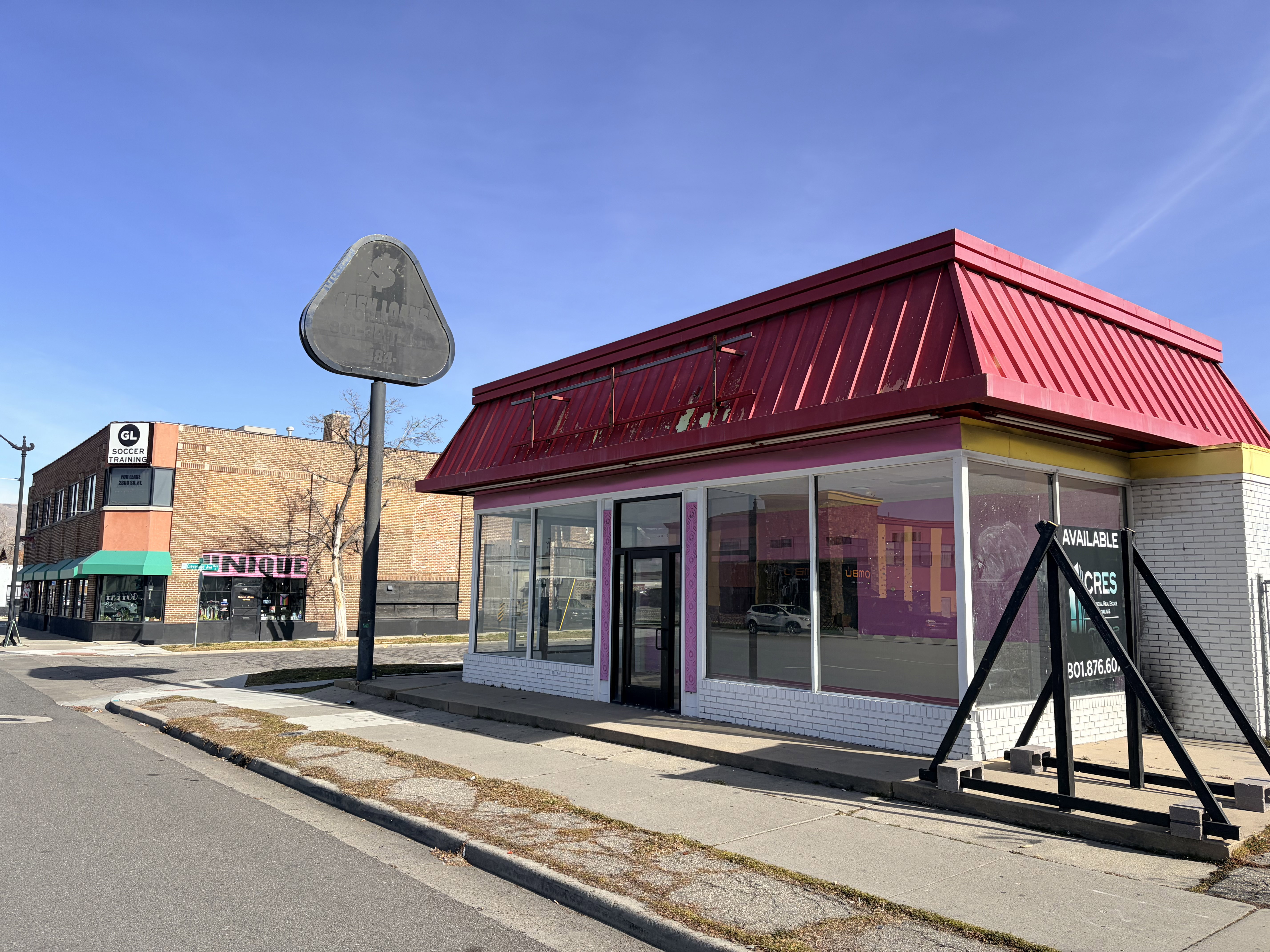 Commercial building featuring a prominent red metal roof and expansive storefront windows