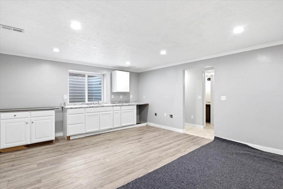 Finished basement space featuring recessed lighting, light wood-finish flooring, and a built-in kitchenette