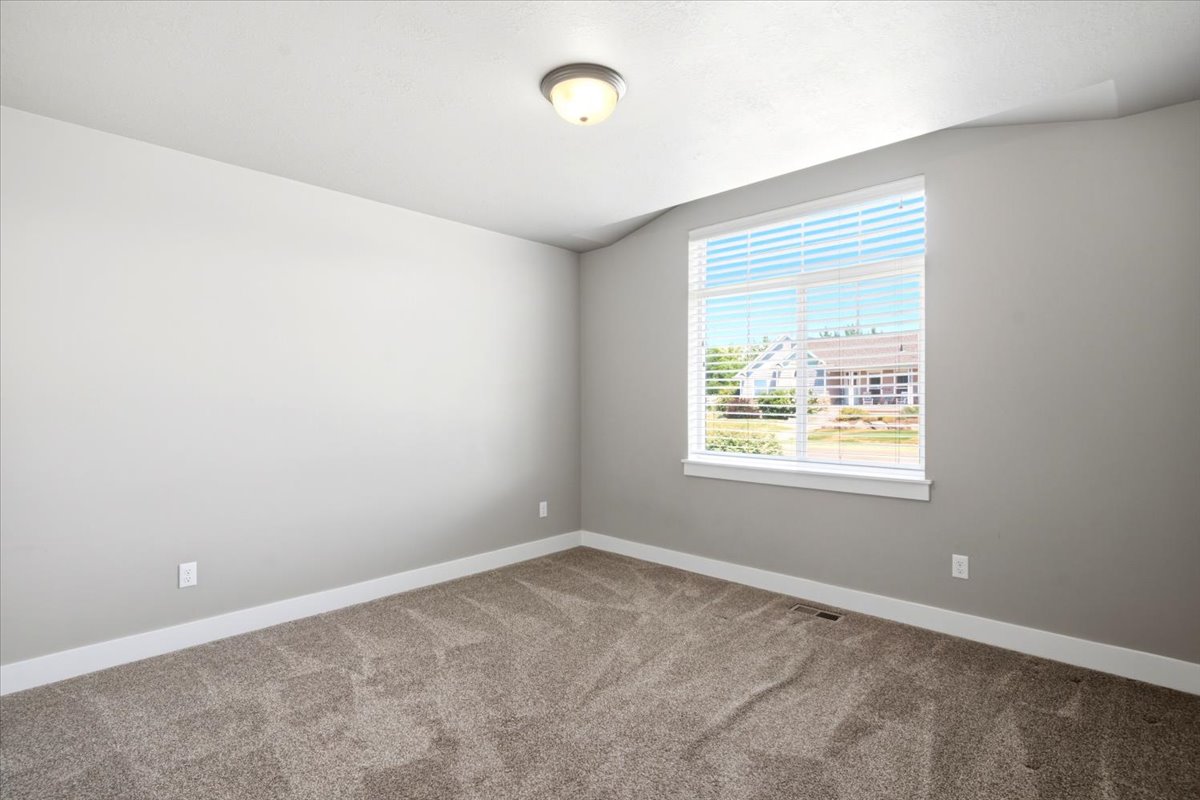 Carpeted room featuring a large window with white blinds, neutral gray walls, and white trim