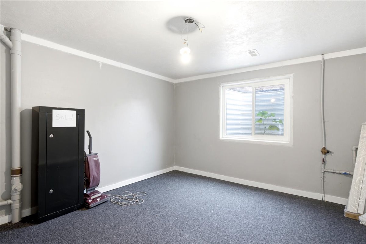 Room featuring gray wall paint, white crown molding, dark gray carpeting, and a white-framed window
