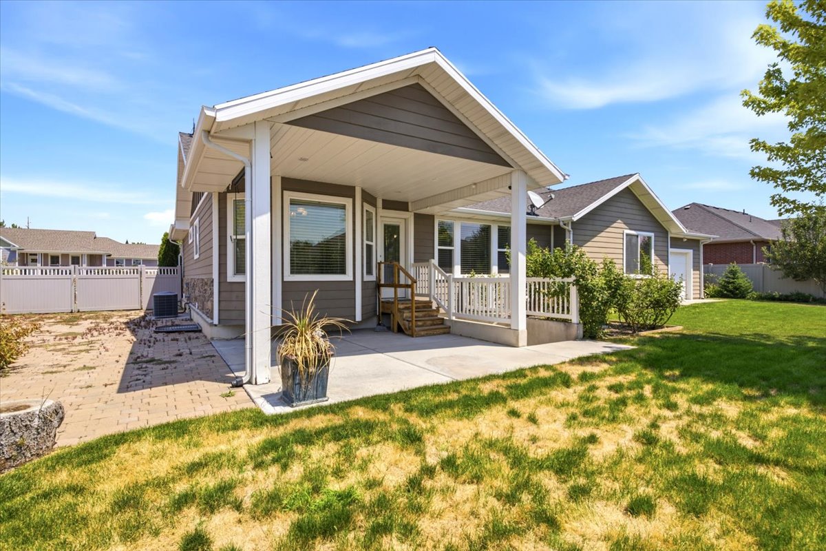 Covered patio area with concrete flooring, accented by a white railing and supporting columns