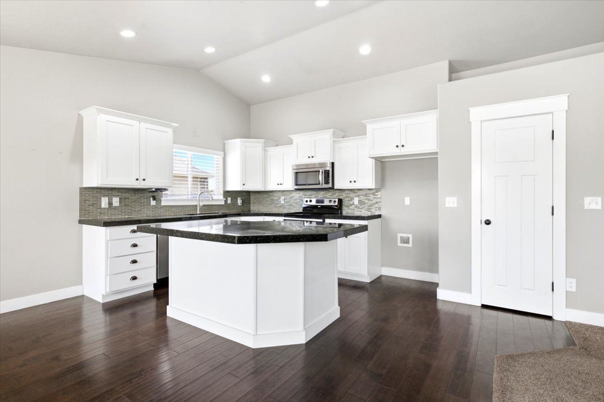 Kitchen featuring white cabinetry, dark countertops, and a tile backsplash