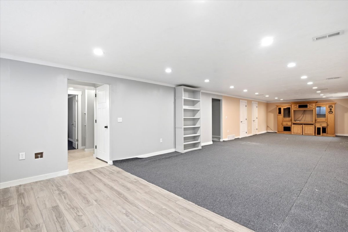 Spacious lower-level room featuring recessed lighting, a built-in shelving unit, and a built-in media center