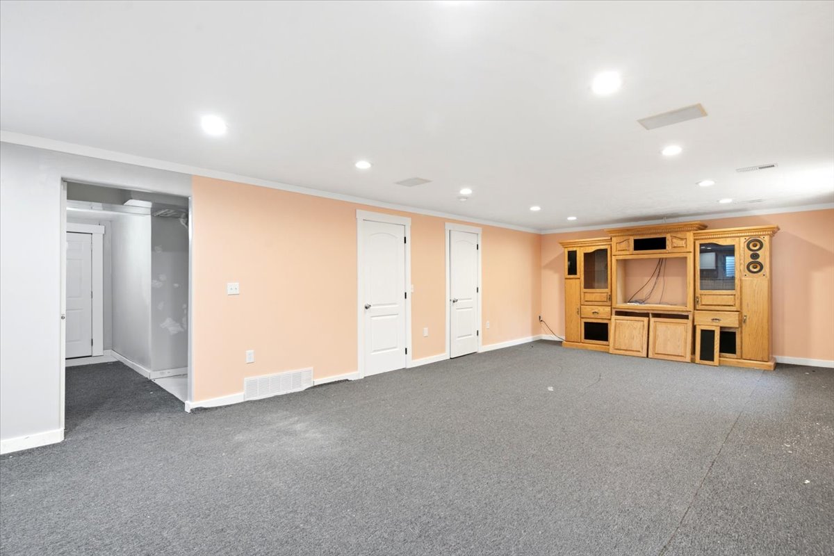Spacious room featuring light peach walls, recessed lighting, and a built-in wood entertainment center with display cabinets