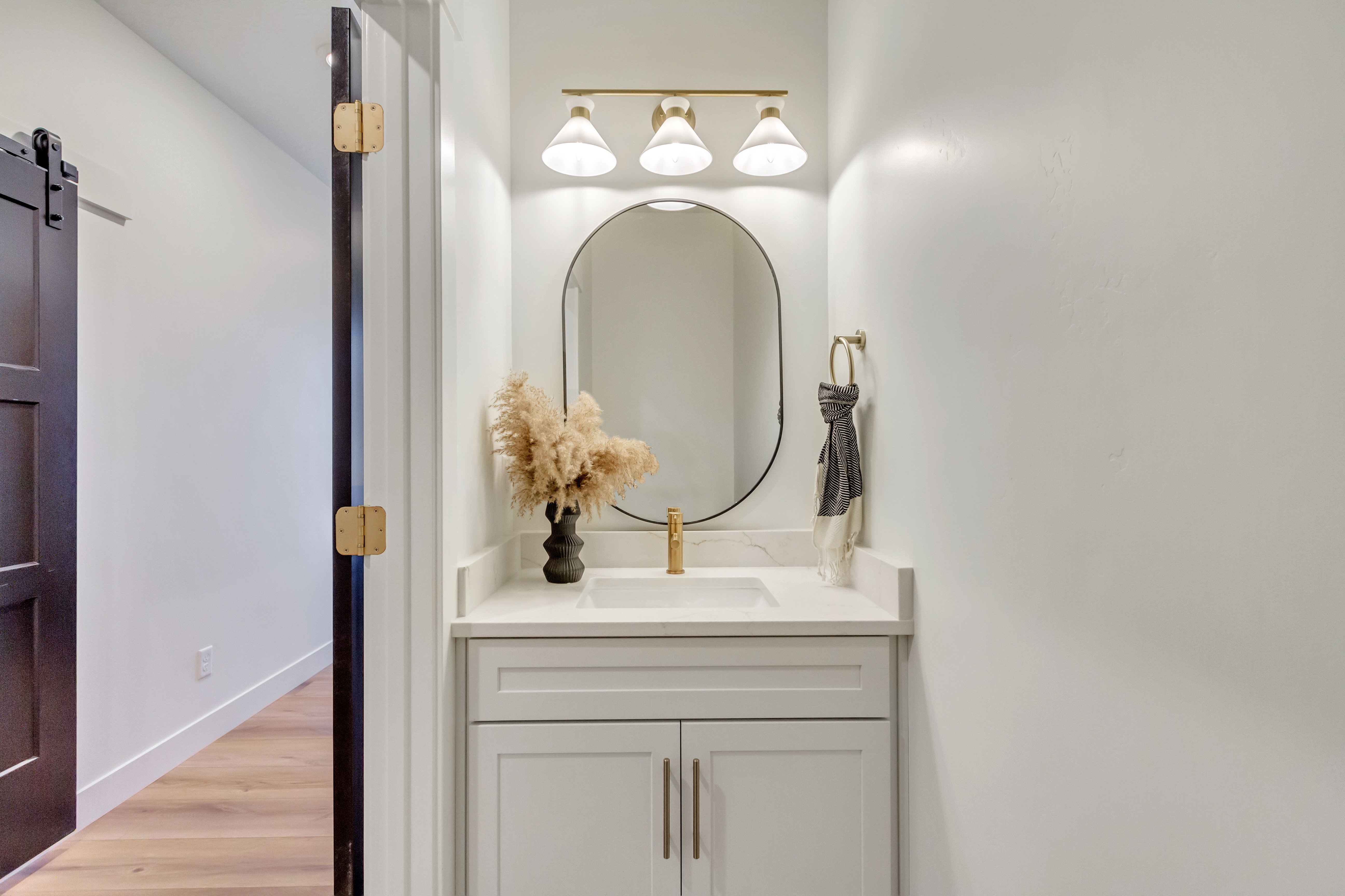 Contemporary vanity featuring a white countertop, under-mount sink, and gold-finish faucet