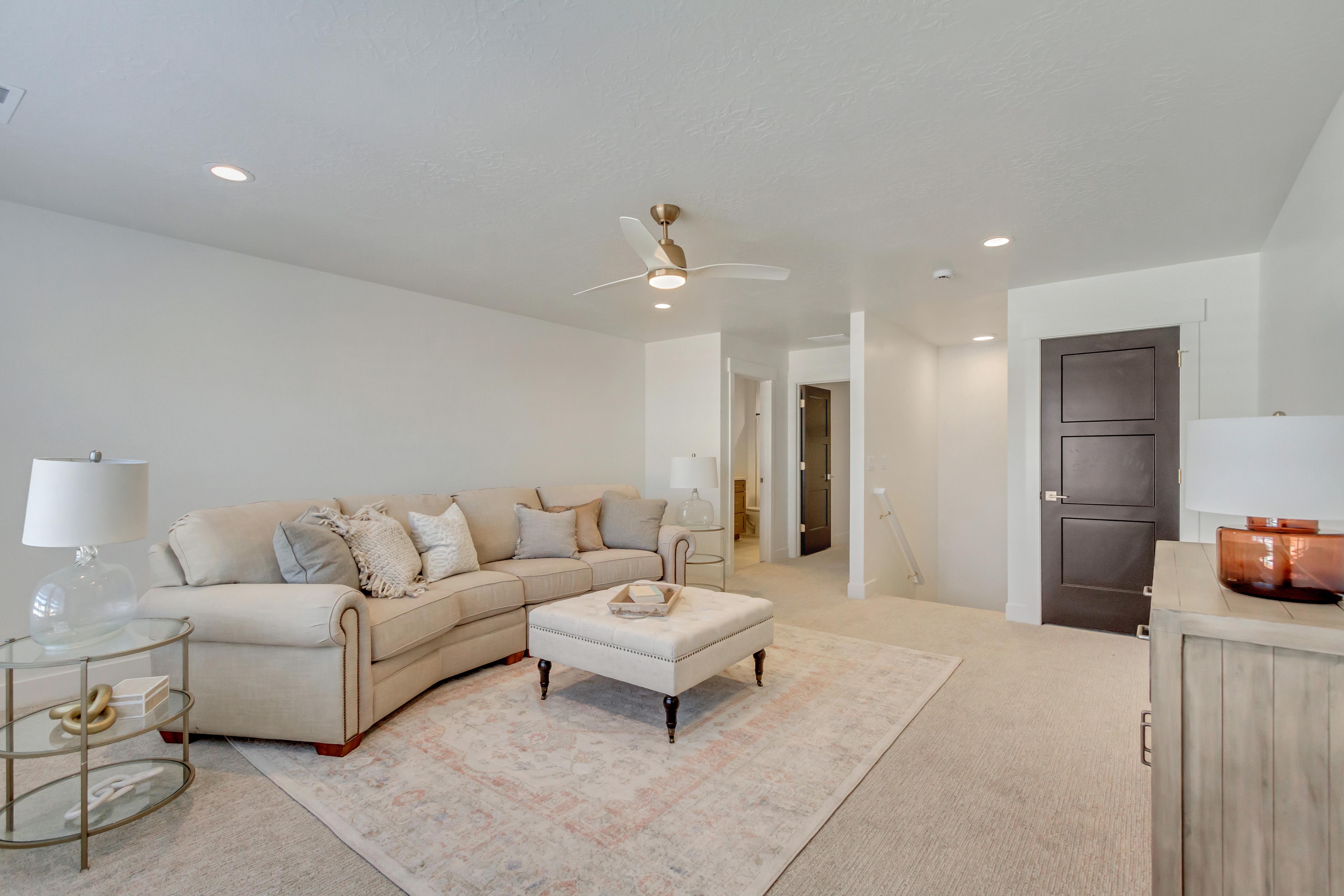 Recessed lighting illuminates the carpeted living area with a ceiling fan