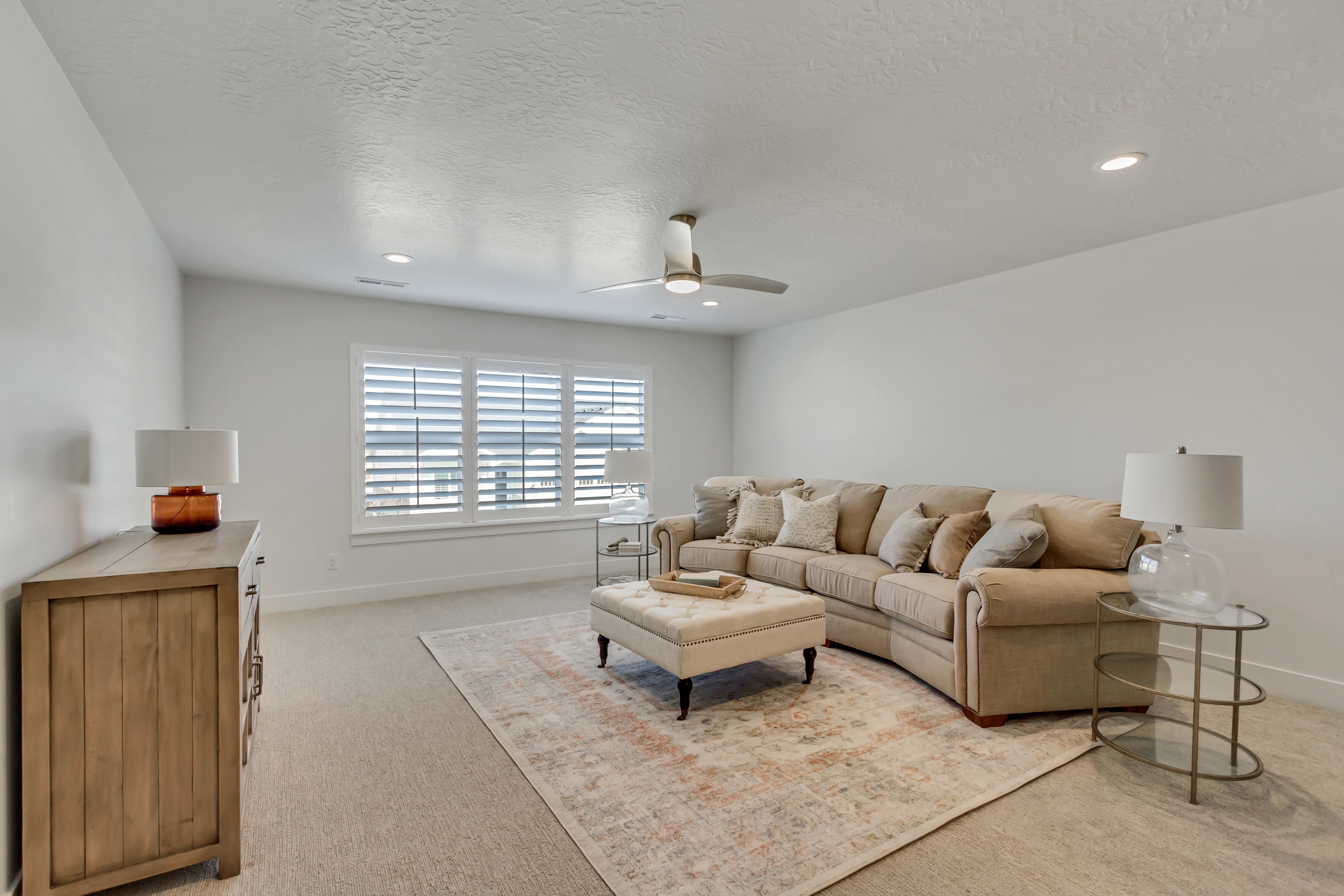 Carpeted room featuring multiple windows with plantation shutters, a ceiling fan, and recessed lighting