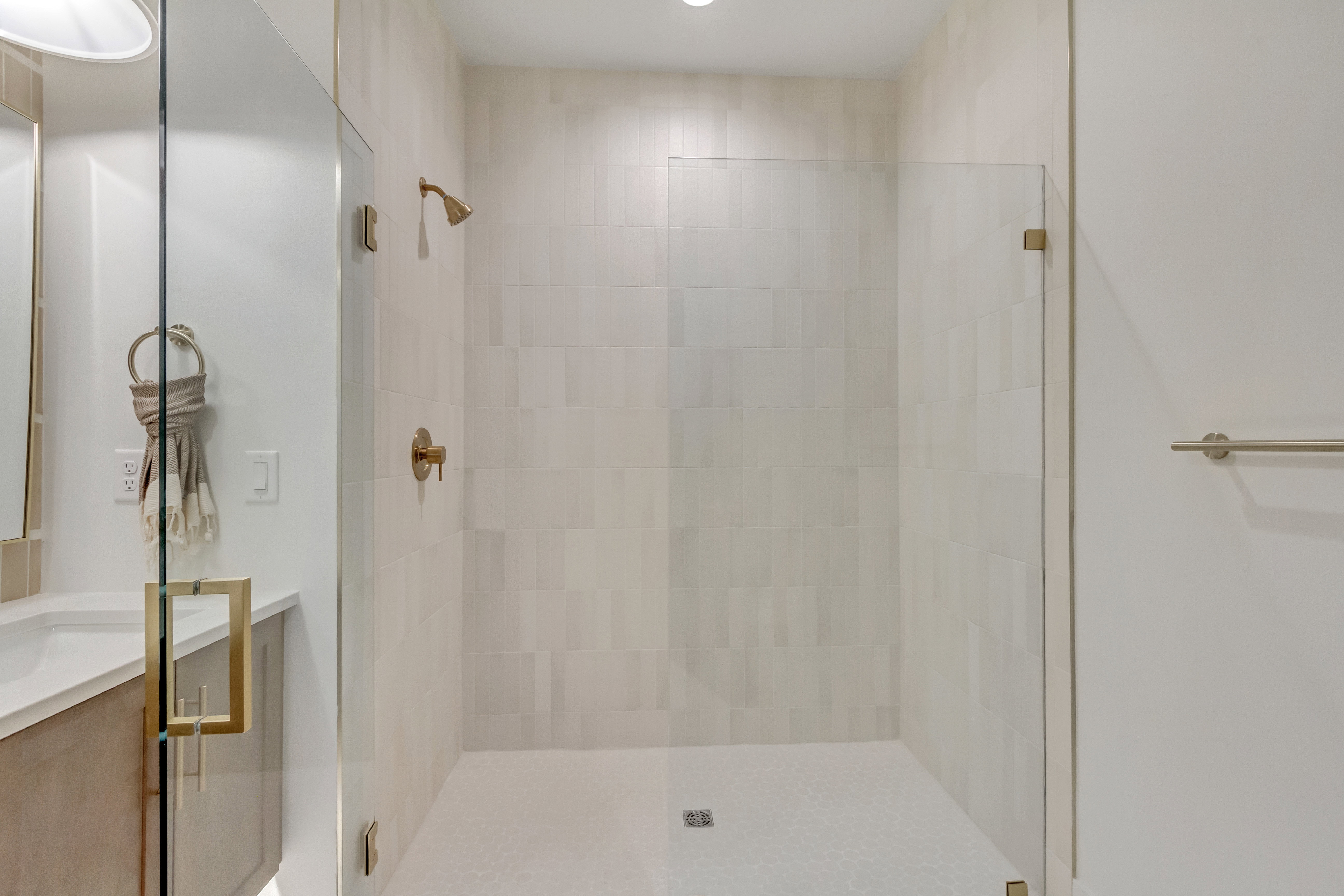 Walk-in shower with clear glass enclosure and brass hardware
