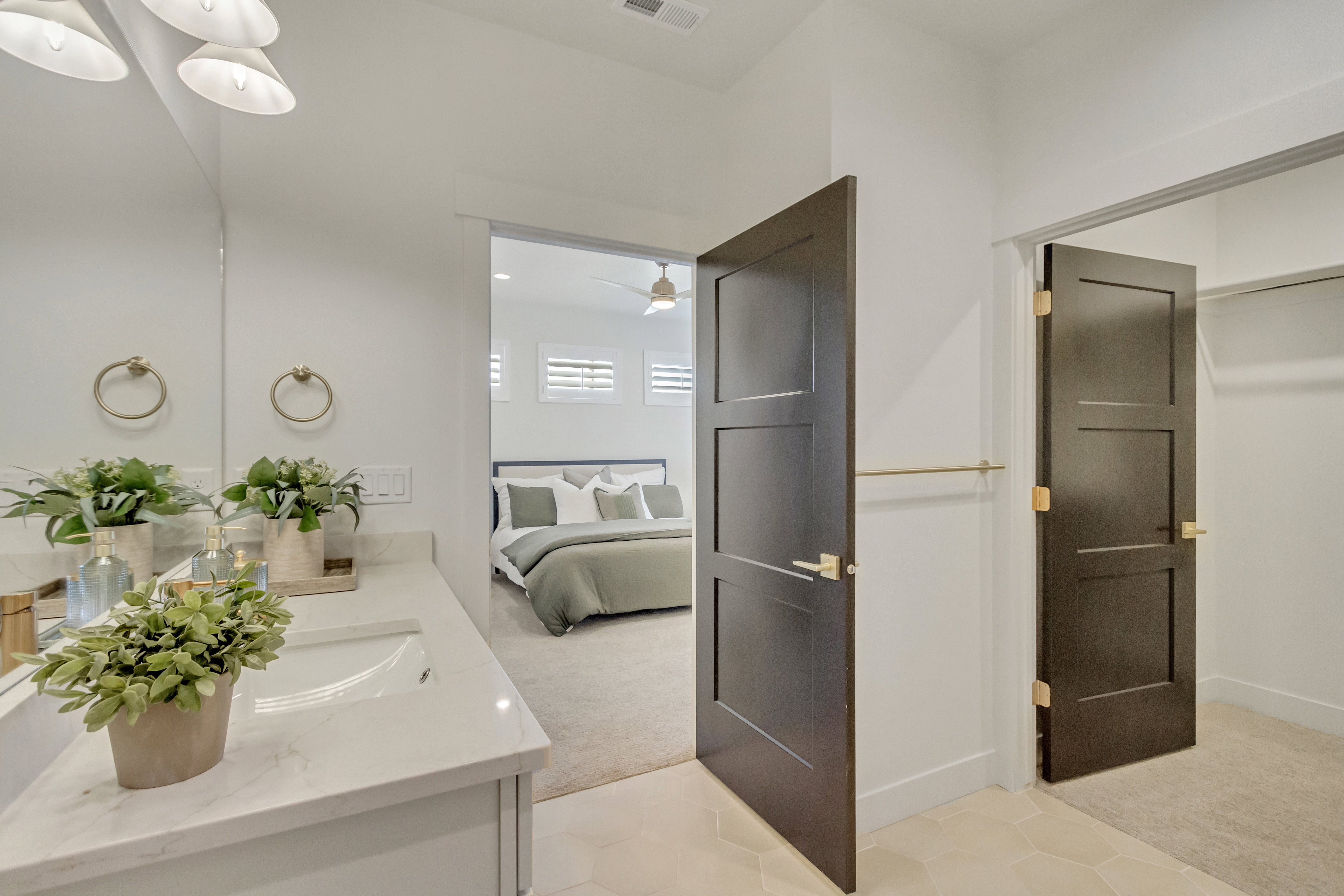 Well-appointed bathroom featuring a single vanity with a light-toned countertop and integrated sink, dual mirrors, and brushed gold towel rings