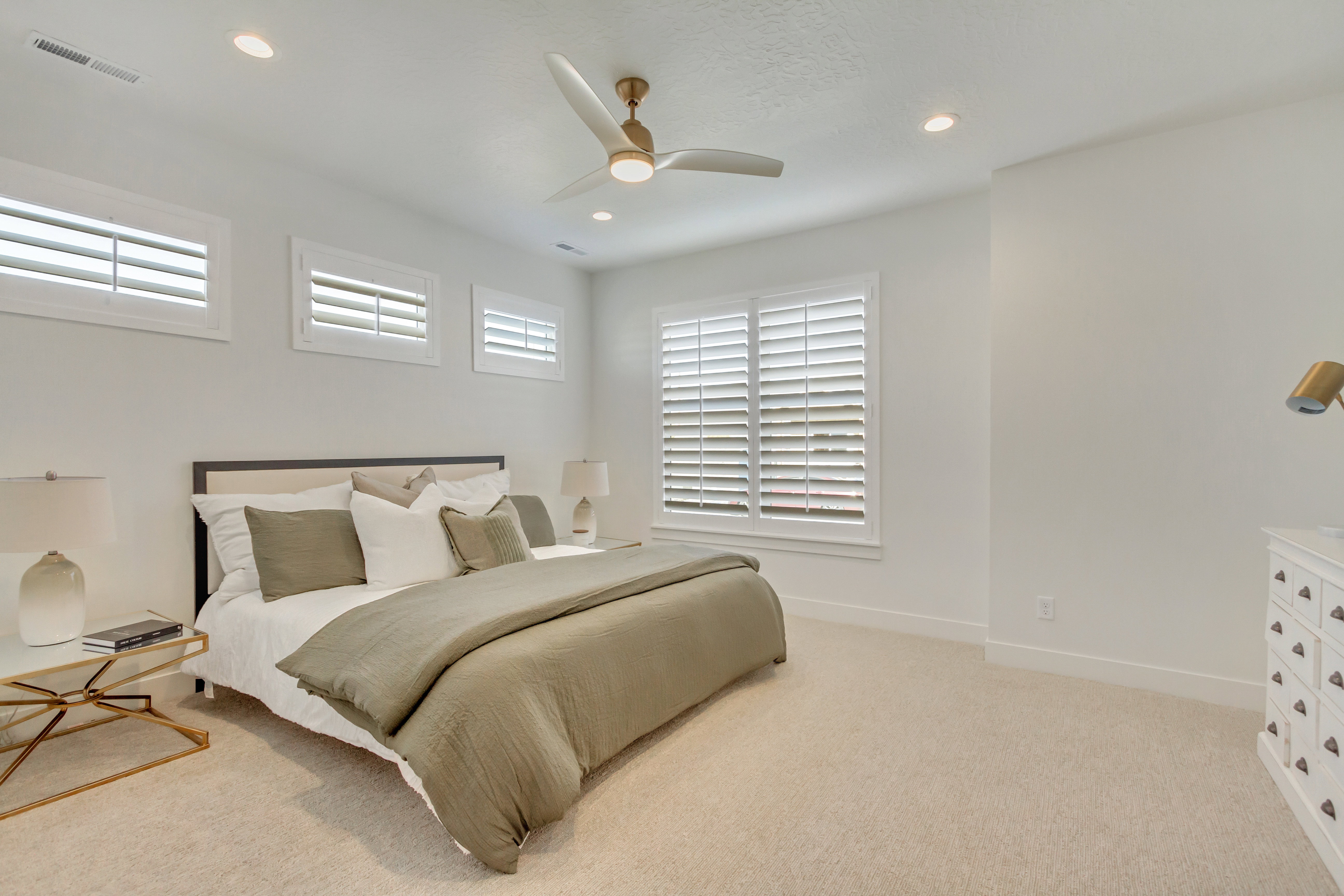 Light-filled bedroom featuring plush carpet flooring, recessed lighting, a contemporary ceiling fan, and multiple windows with plantation shutters
