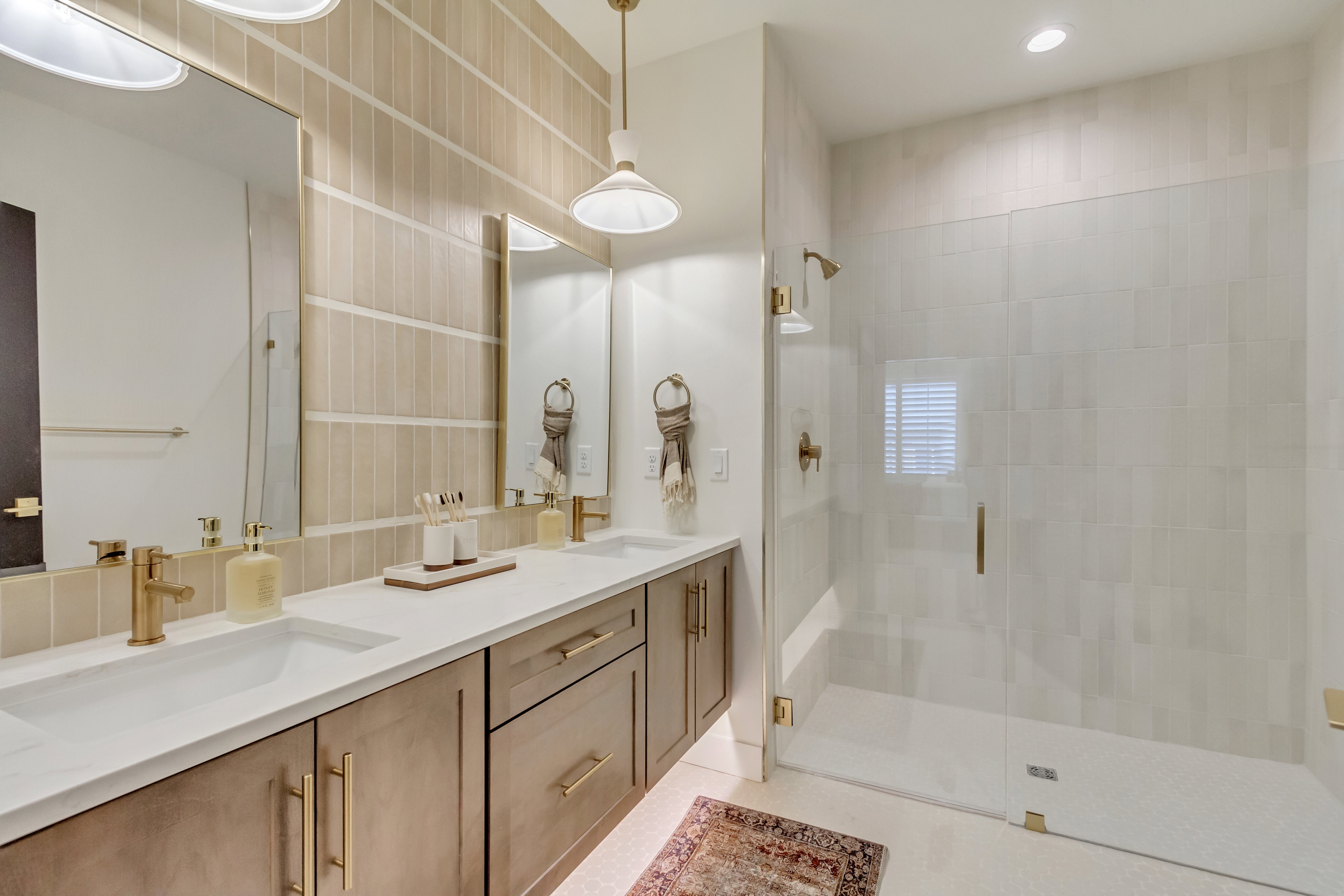 Bathroom featuring a dual vanity with undermount sinks, white countertops, and warm-toned cabinetry