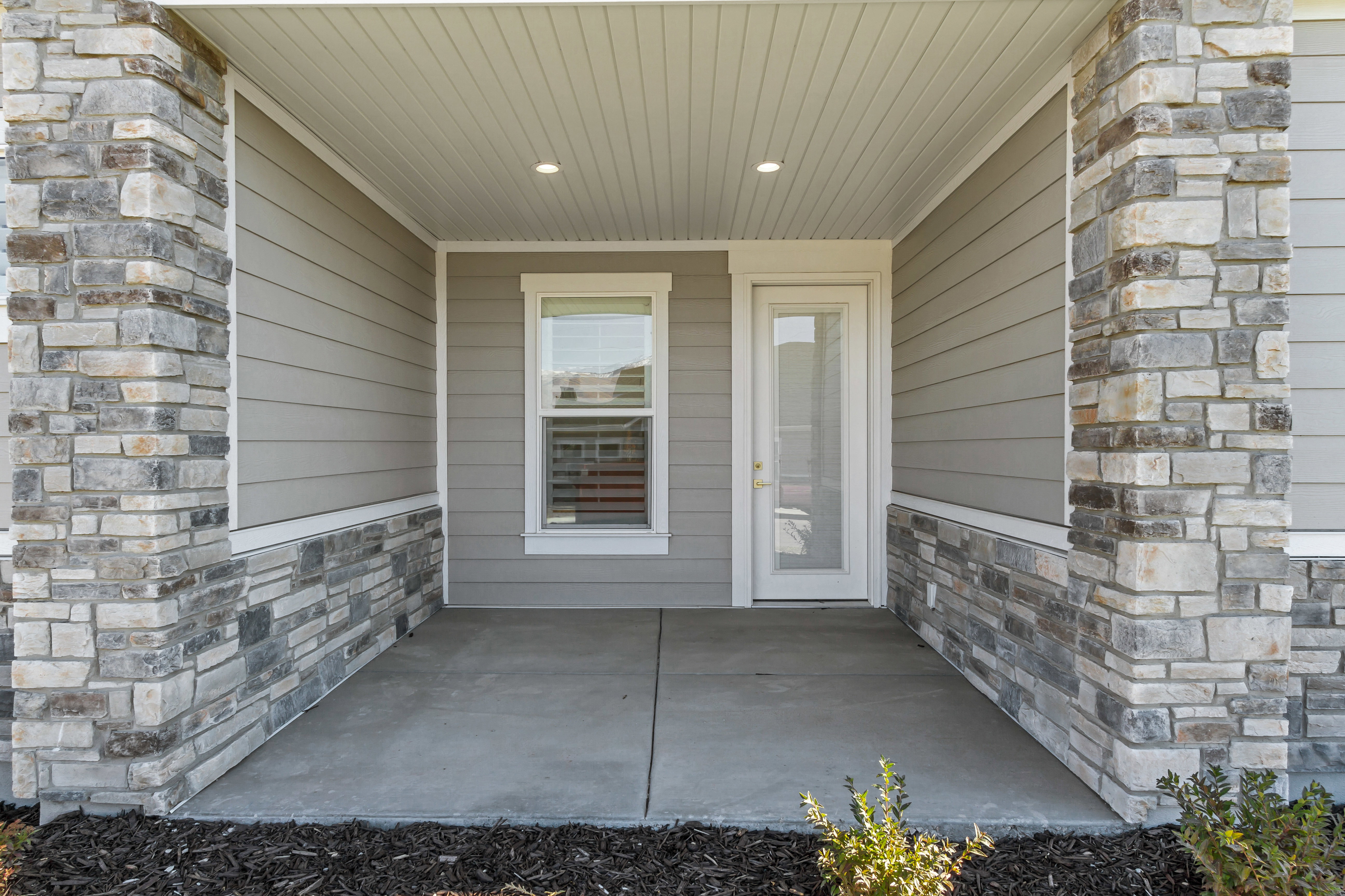 Covered front porch featuring stone veneer columns and foundational accents