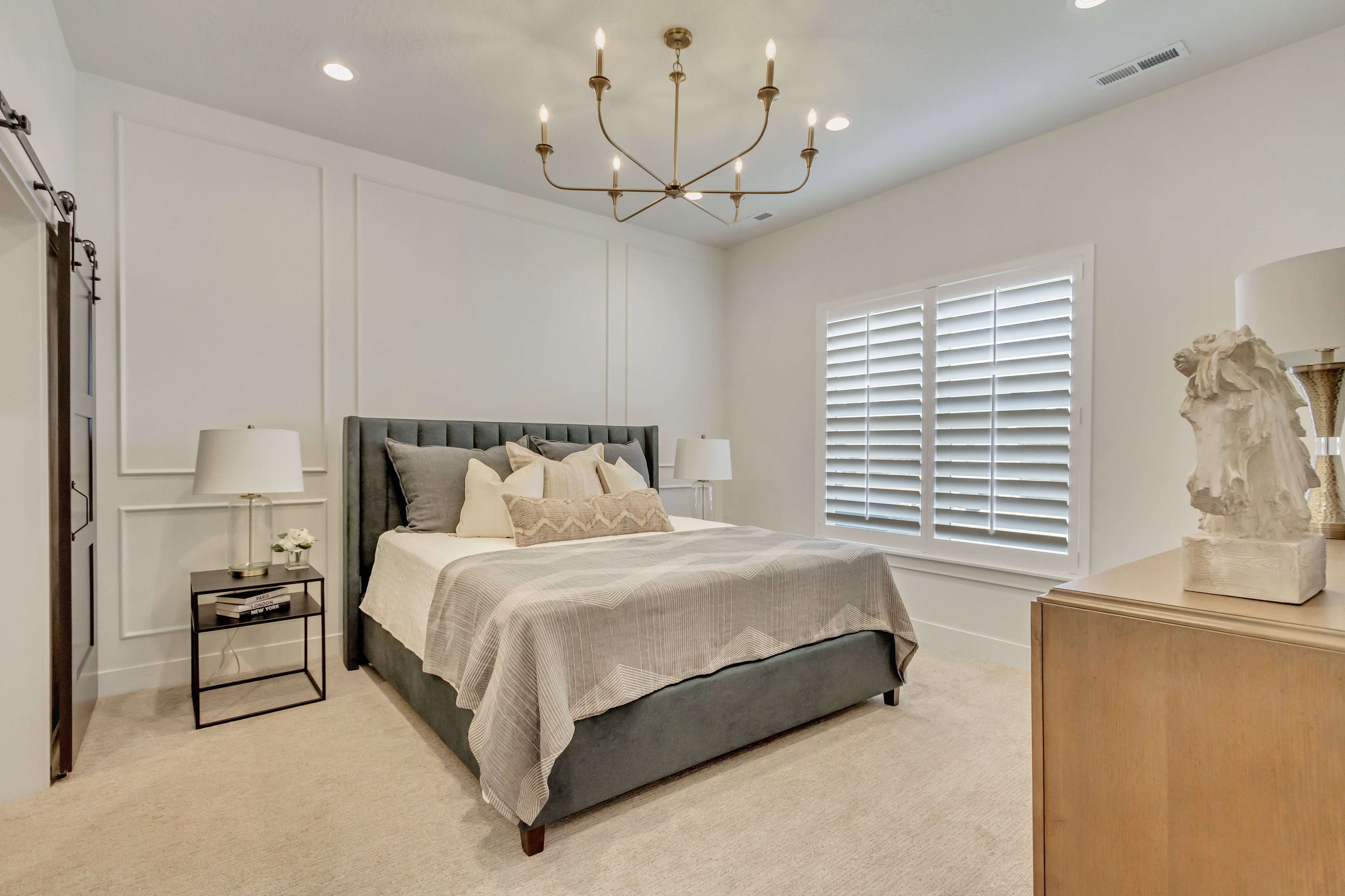 Bedroom featuring a paneled accent wall, a bronze chandelier, recessed lighting, and plantation shutters