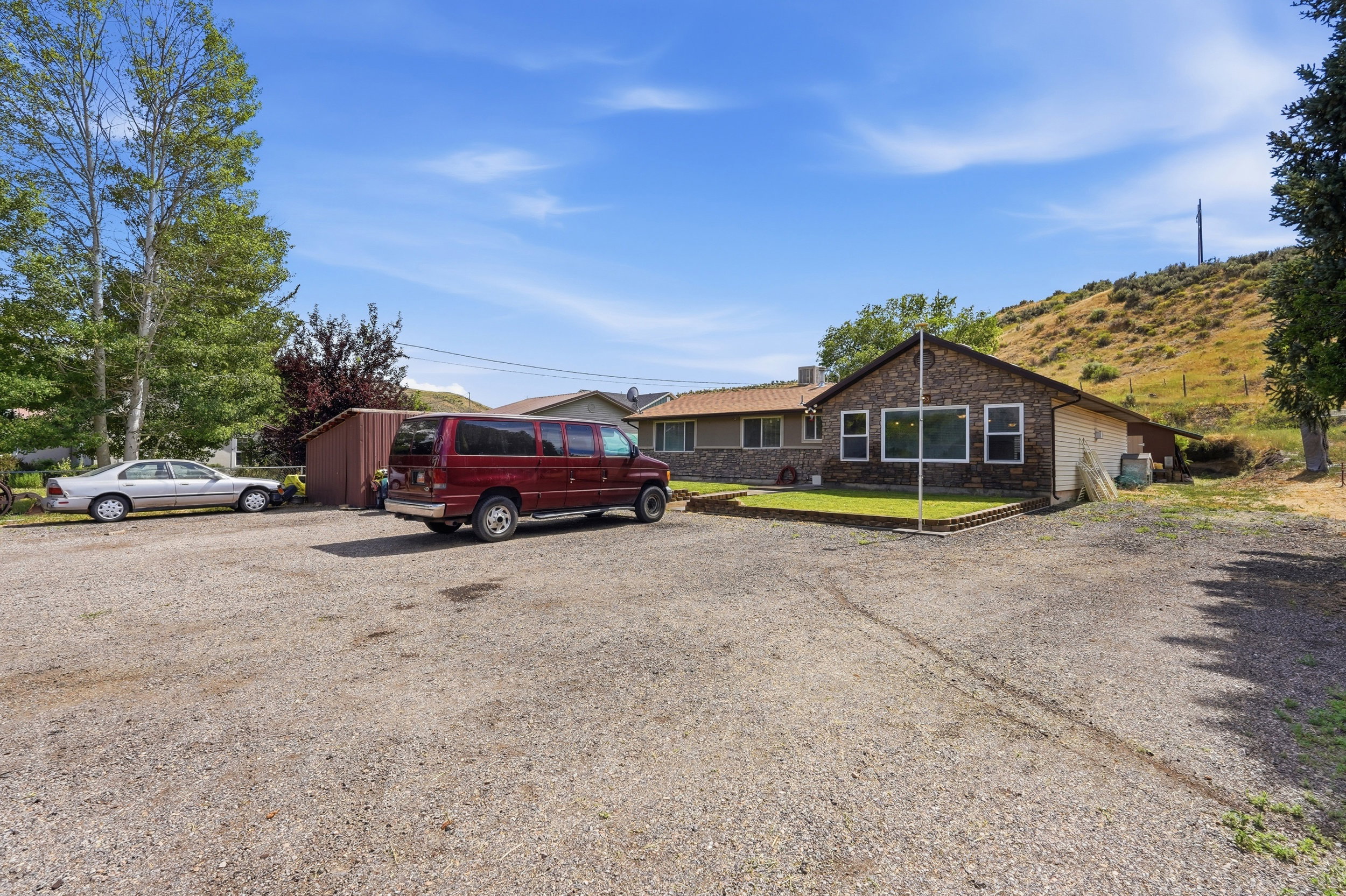 Ranch-style residence featuring a stone facade and a gravel parking area