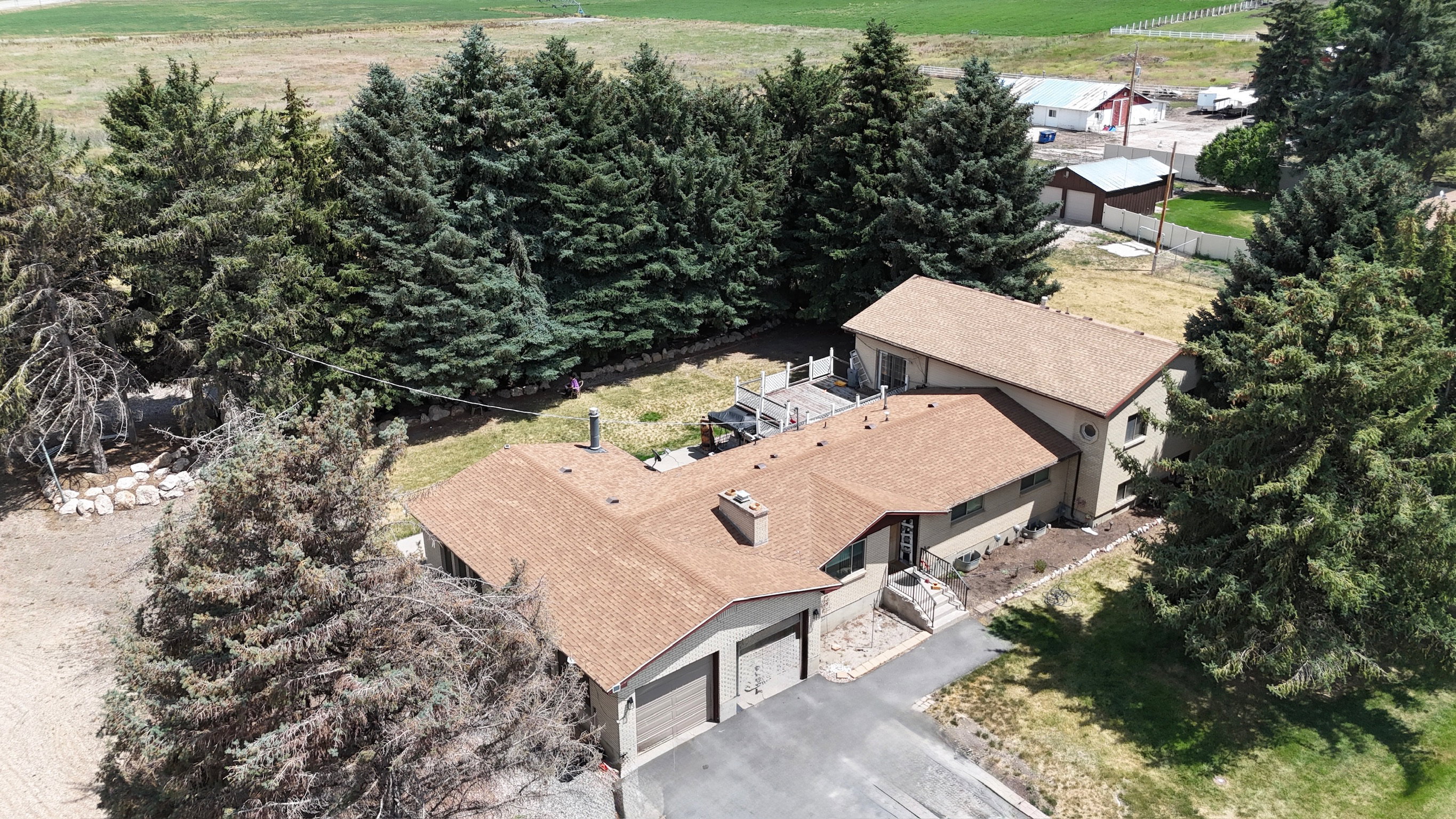 Expansive property featuring a multi-level residence with a brown shingle roof, attached two-car garage, and a rear deck