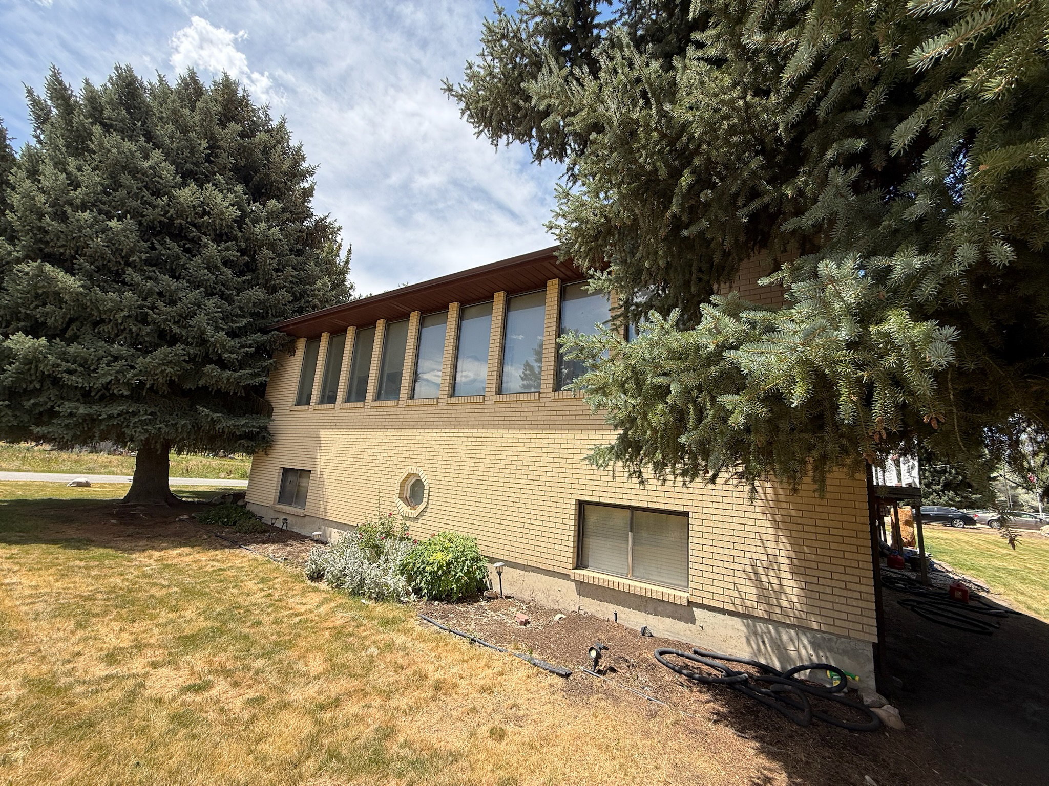 Light yellow brick exterior featuring a prominent upper-level window bank with vertical accents, and a distinctive circular window on the lower level
