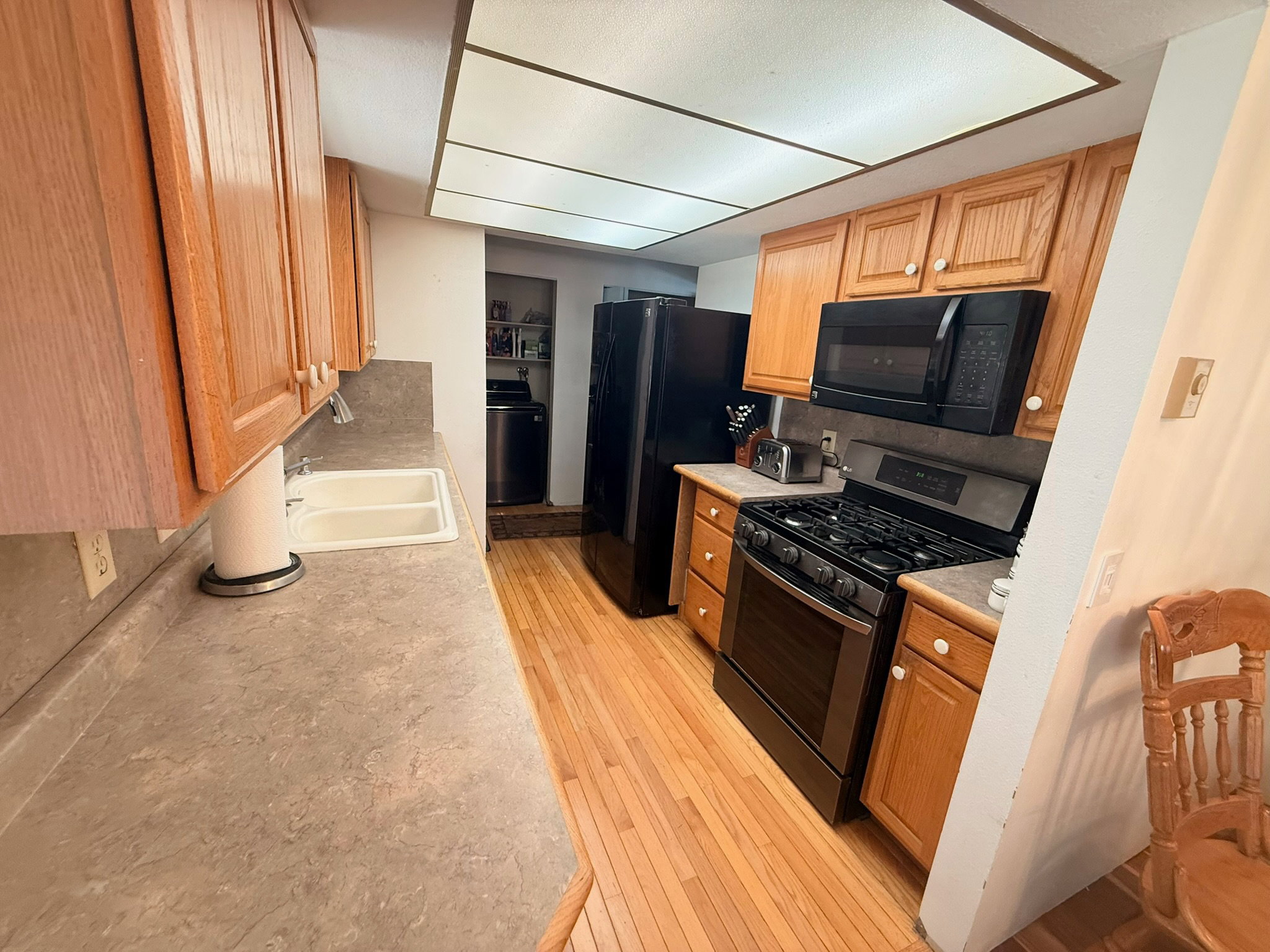 Kitchen featuring wood-finish flooring, light wood cabinetry, and neutral countertops