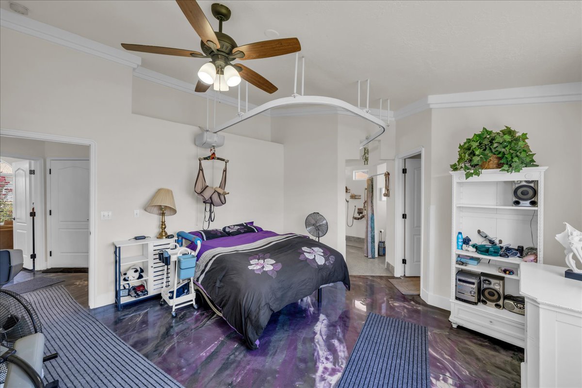 Spacious room featuring high ceilings, crown molding, a ceiling fan with integrated lighting, and a unique purple-toned polished floor