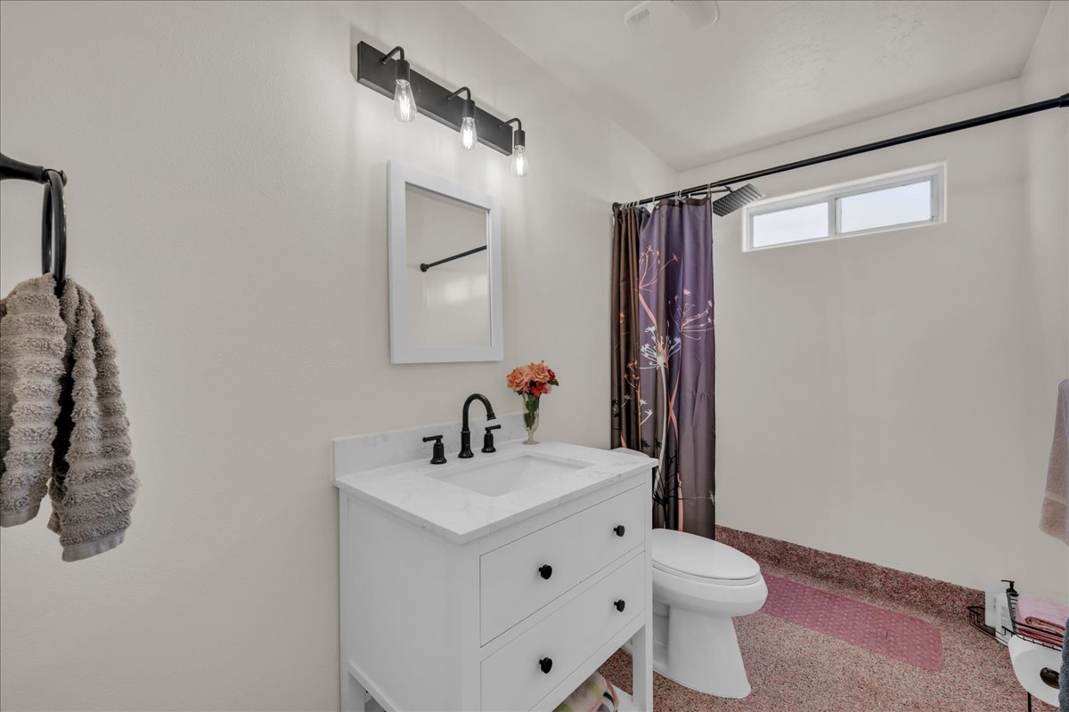 Bathroom featuring a white vanity with a rectangular sink, a white countertop, and matte black fixtures