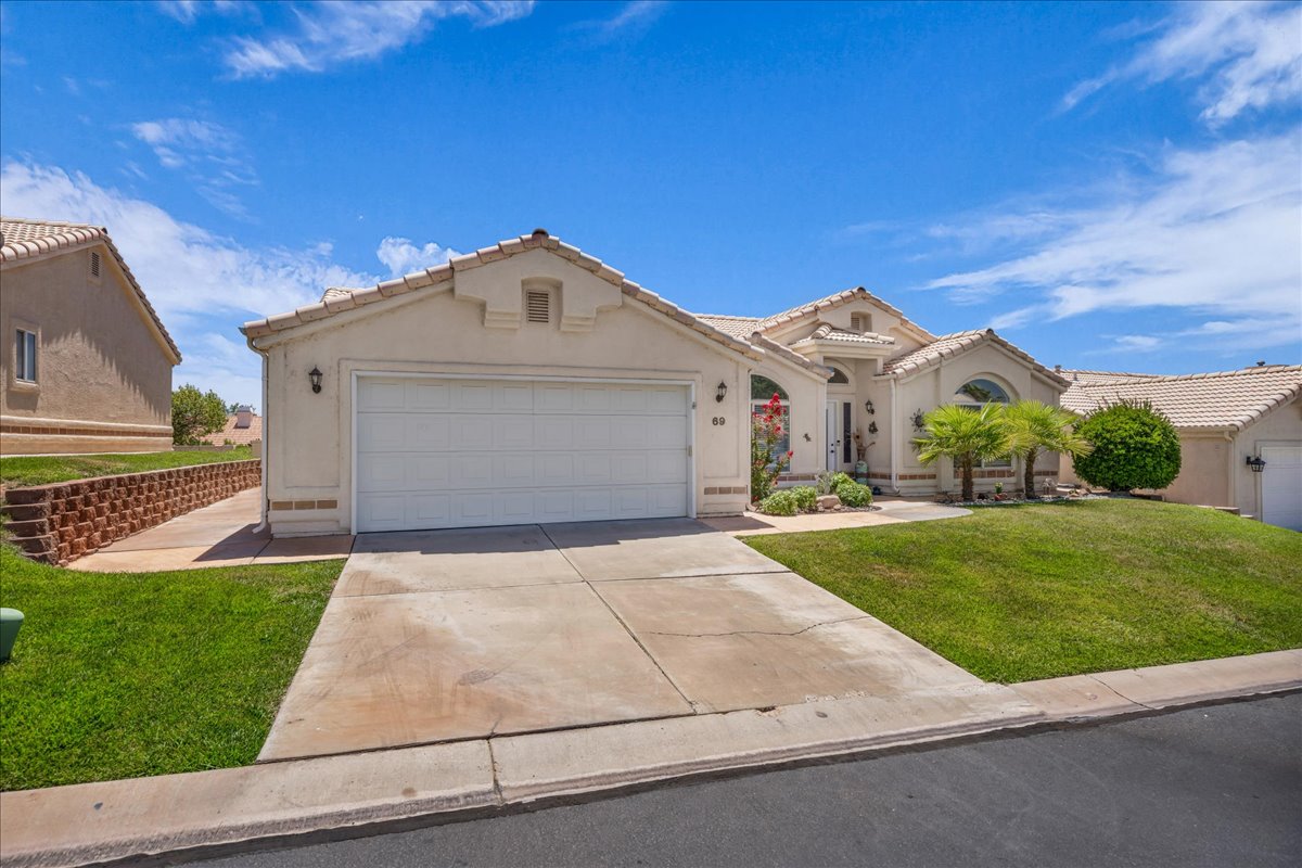 Stucco exterior with a tiled roof, featuring an attached two-car garage and a concrete driveway