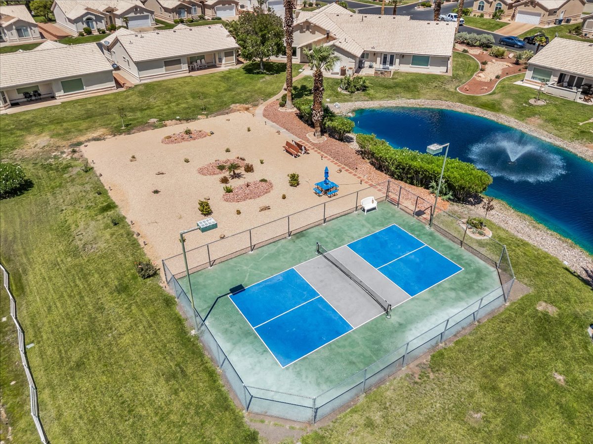 Pickleball court with perimeter fencing, a desert-scaped recreational area, and a water feature