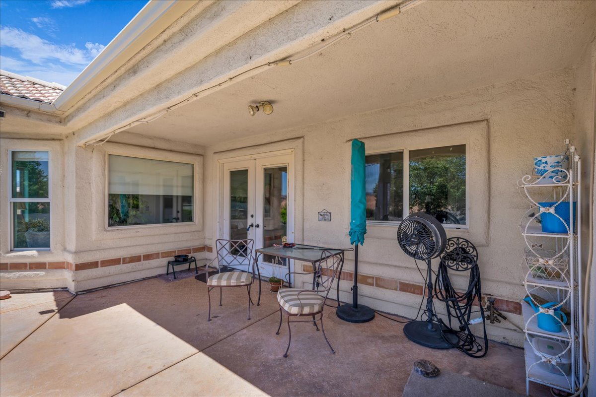 Covered patio featuring concrete flooring, a stucco exterior, multiple windows, and a double glass door entry
