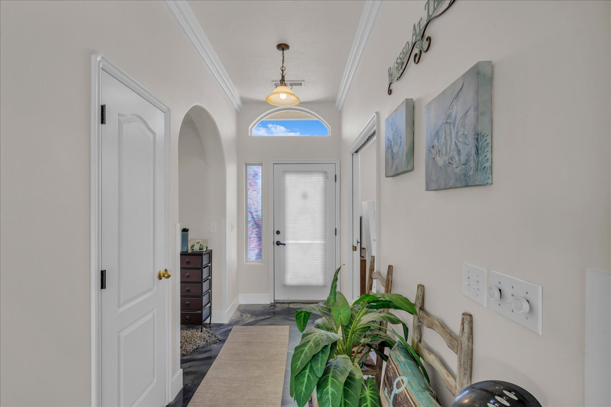 Entryway featuring an arched doorway, crown molding, and a transom window above the front door