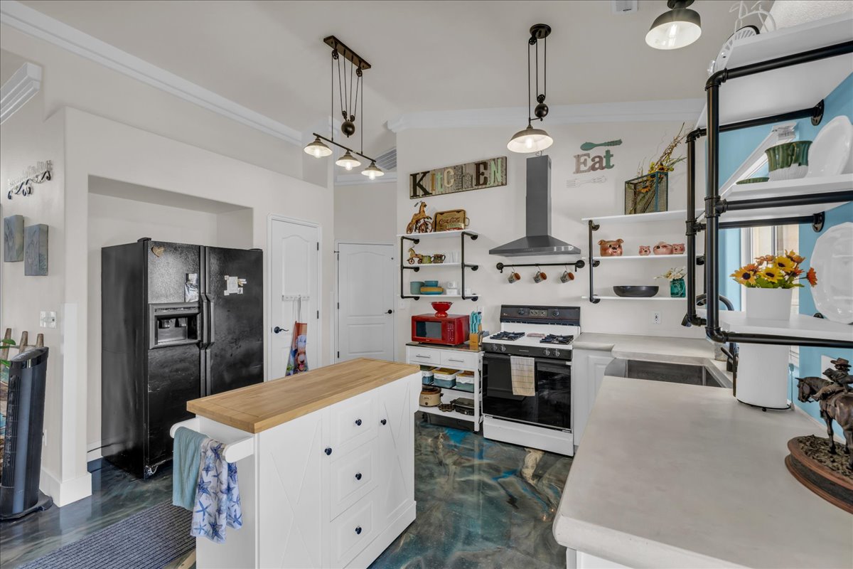 Kitchen featuring industrial-style open shelving, a white gas range with a range hood, and a central island with a wood-finish countertop