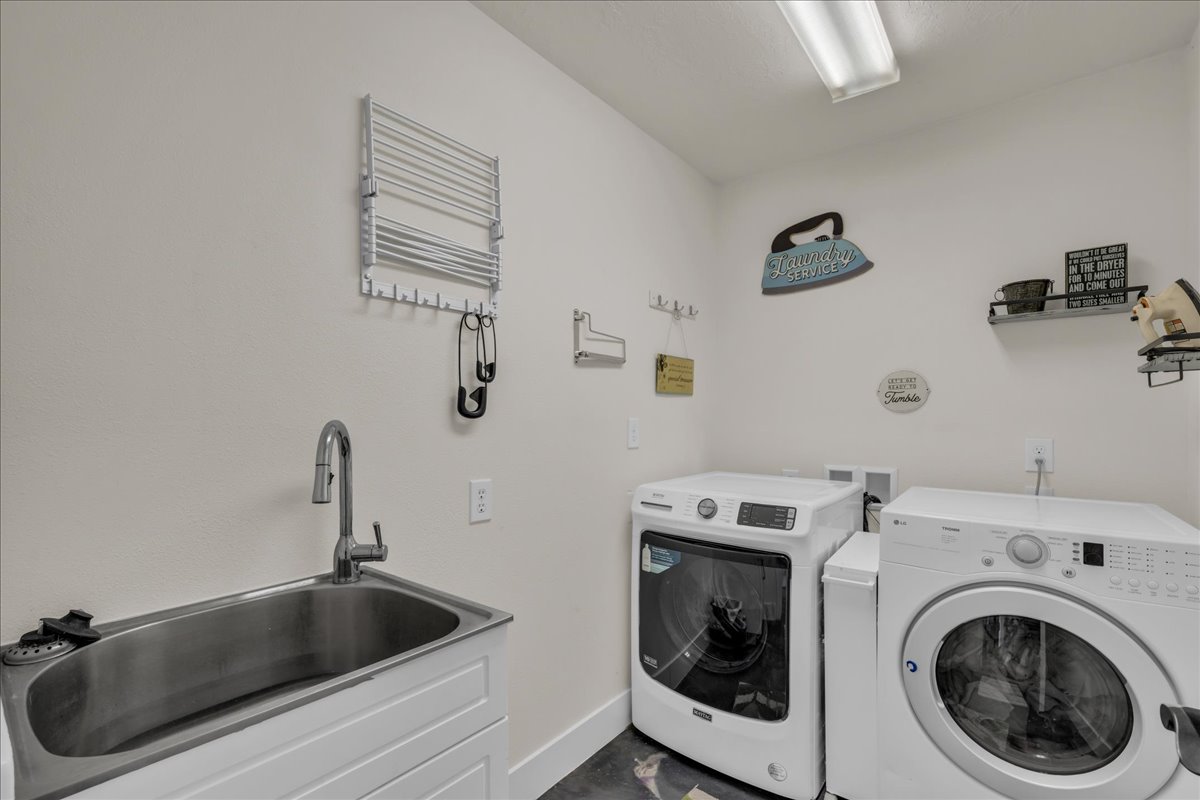 Laundry room featuring a utility sink with a pull-down faucet, white cabinetry, and overhead fluorescent lighting