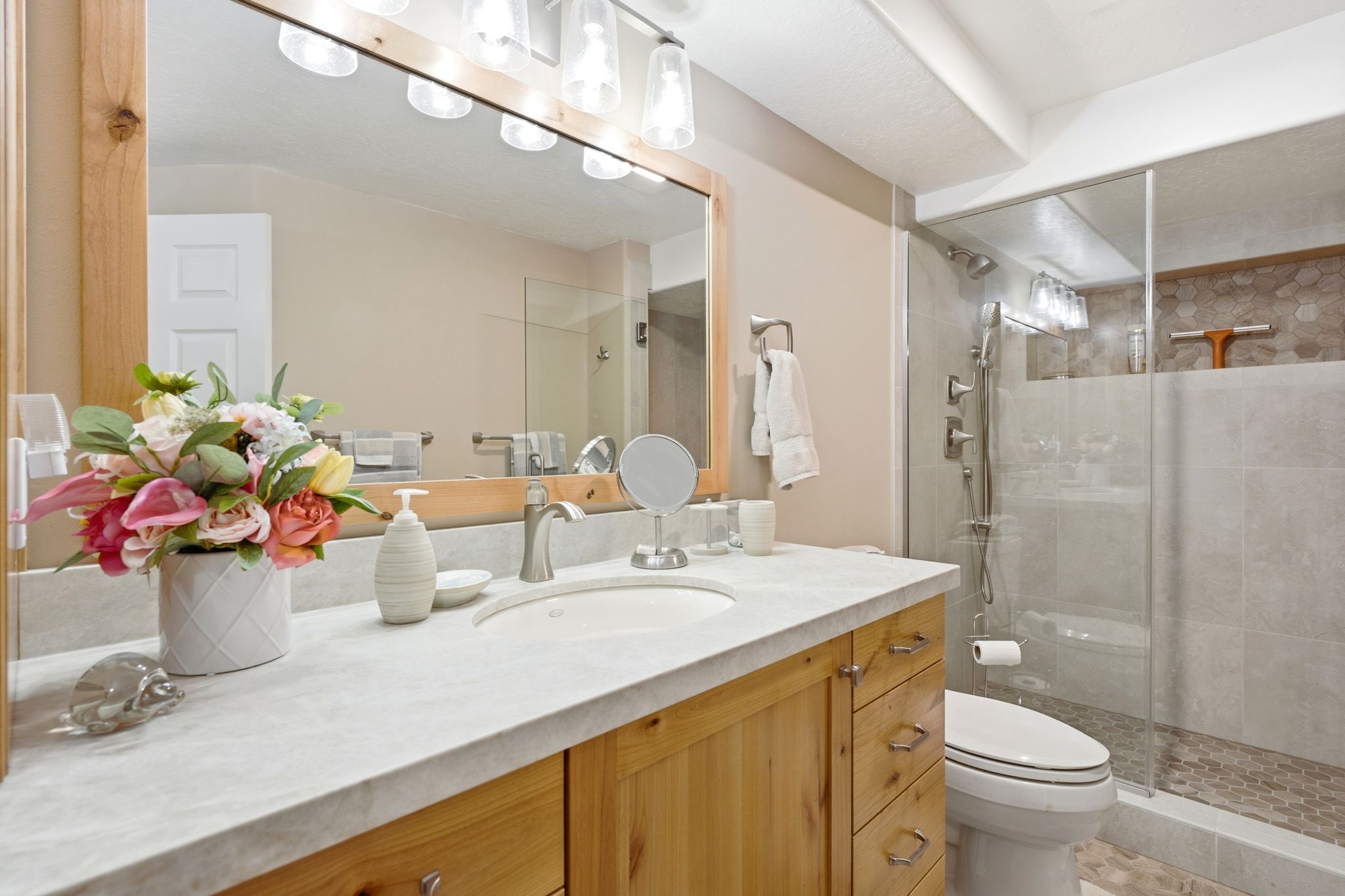 Bathroom vanity with a light wood-finish cabinet and a light-toned countertop