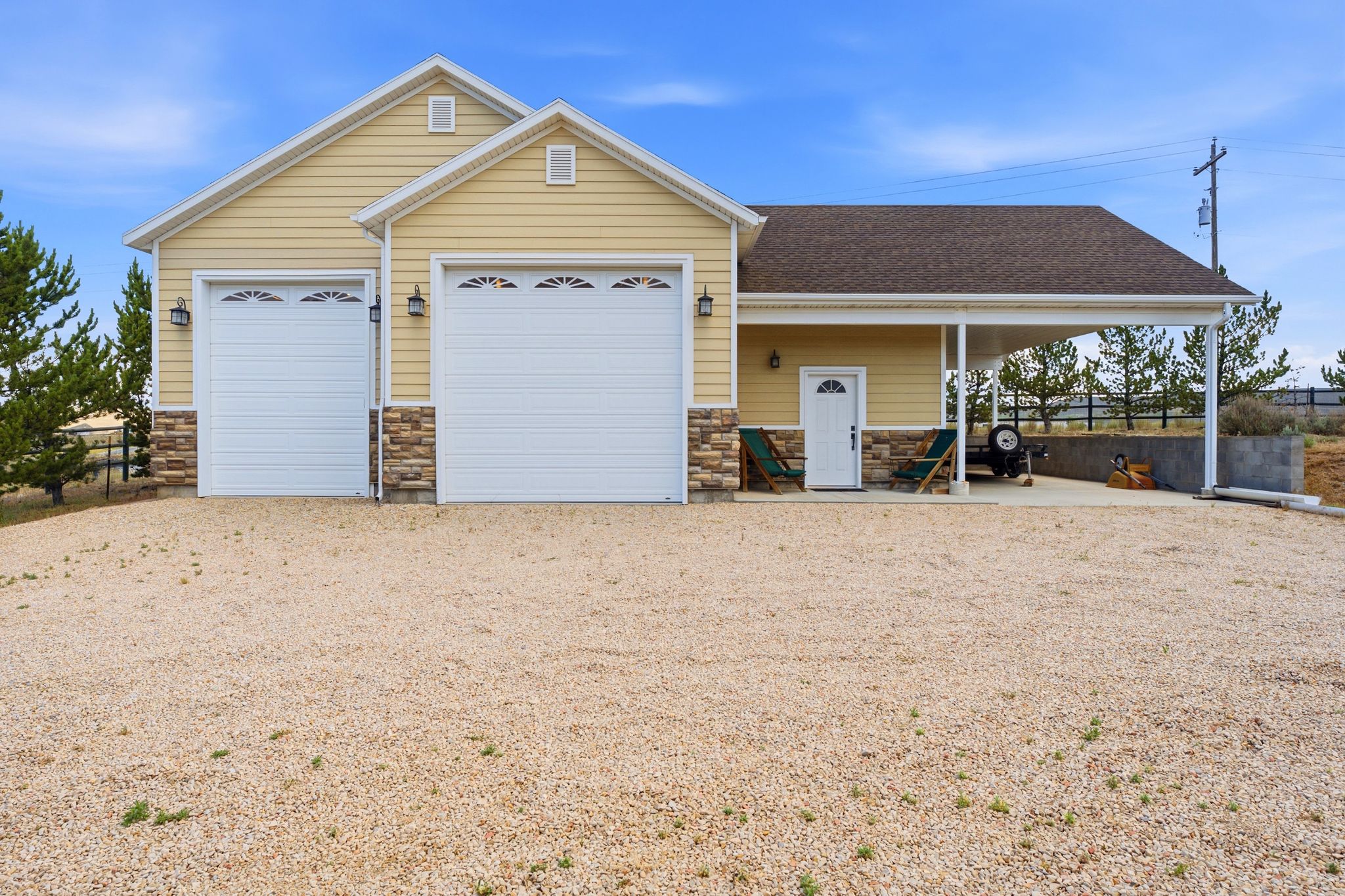 Property exterior featuring dual garage doors with decorative lites, a stone accent facade, and a covered patio area