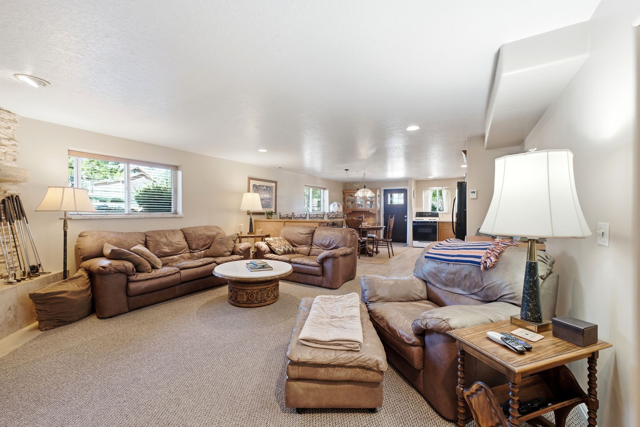Carpeted living area featuring a stone fireplace surround and multiple windows