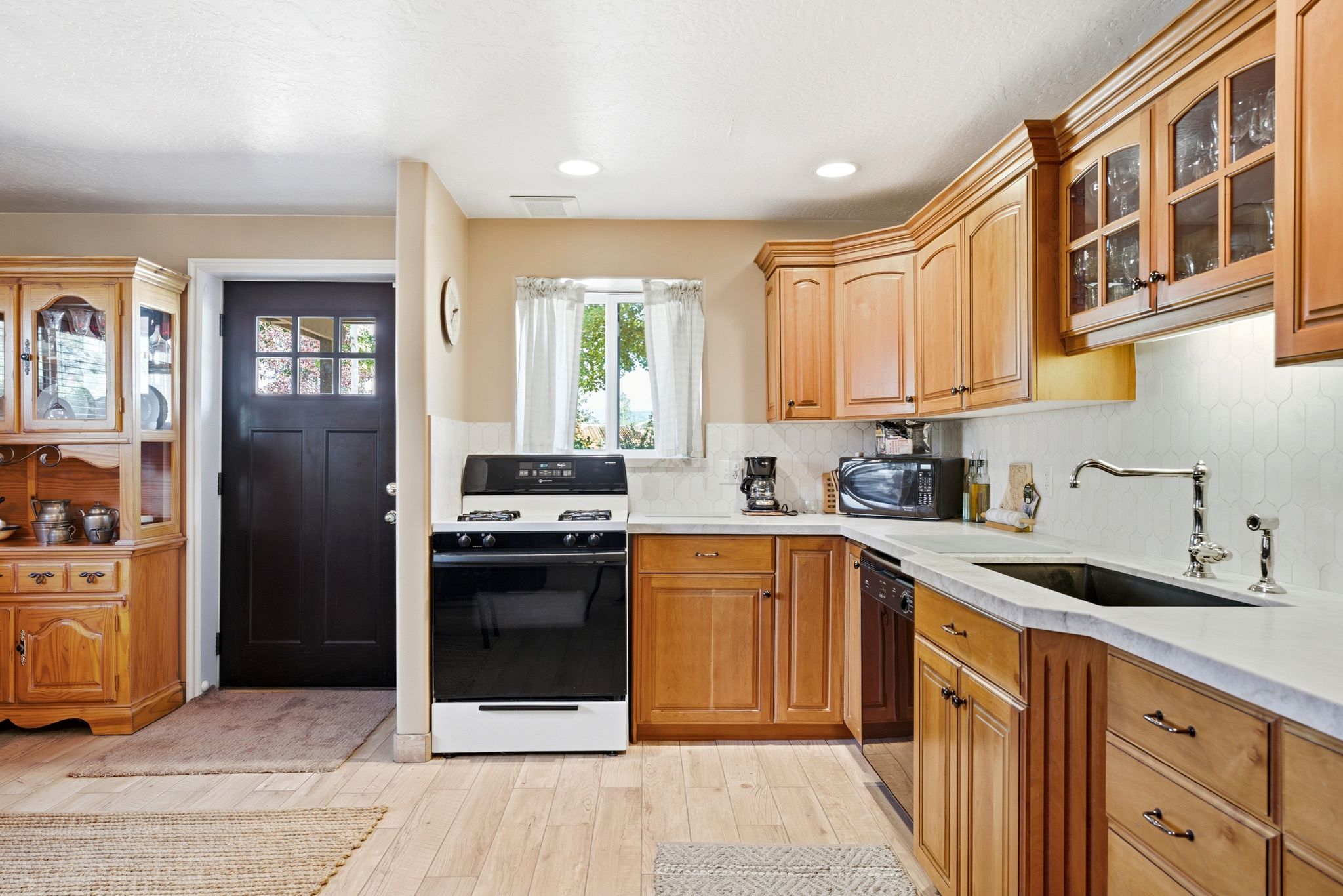 Kitchen with wood-finish flooring, light wood cabinetry, and a white countertop