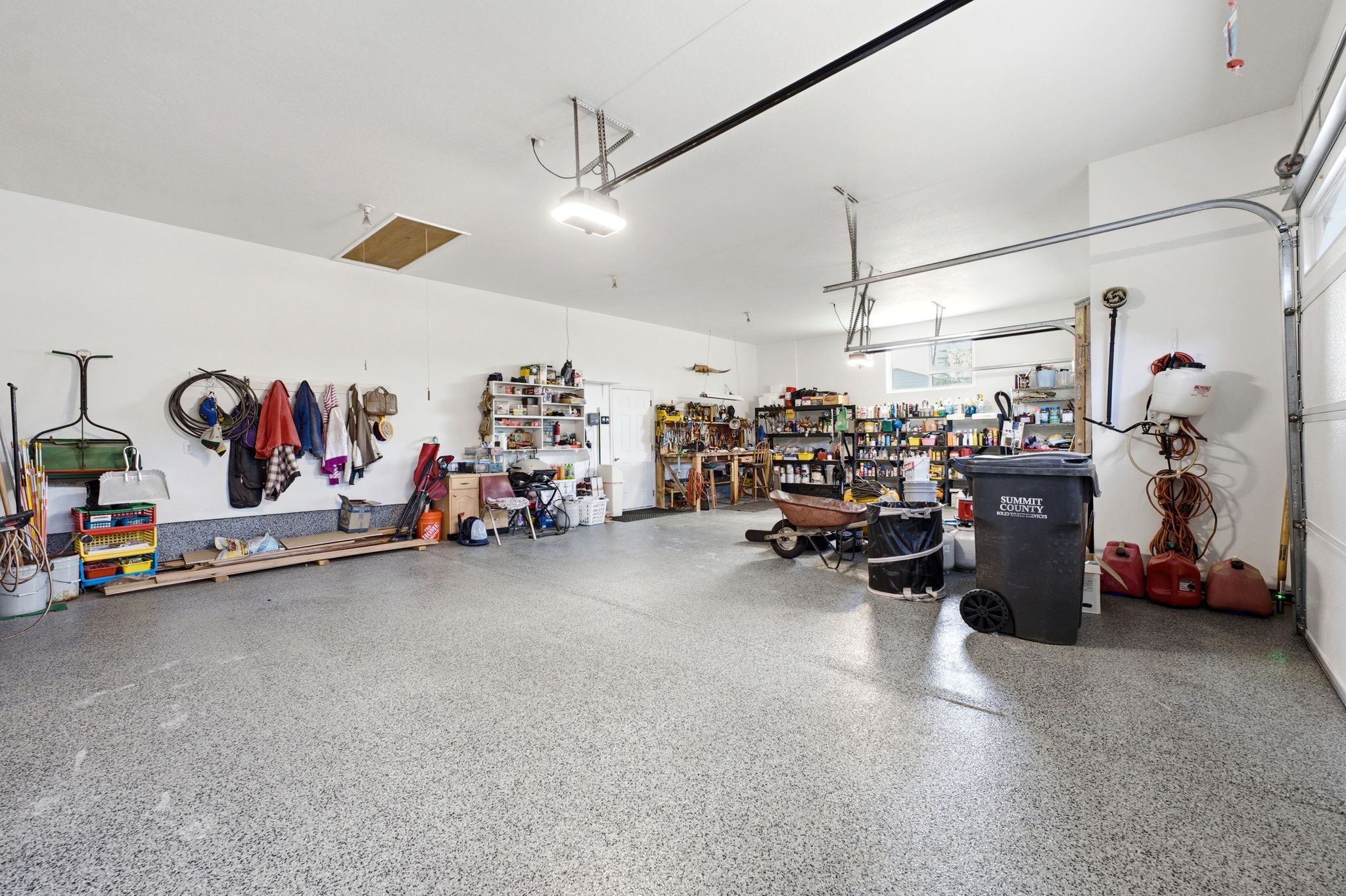 Spacious garage with an epoxy-coated concrete floor, overhead lighting, and white painted walls