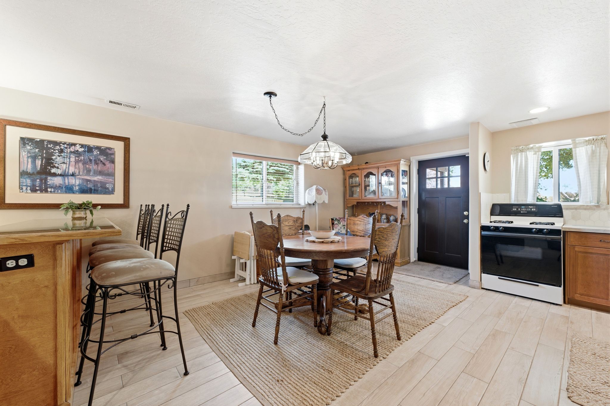 Open-concept living space featuring wood-finish flooring, a built-in breakfast bar, and a functional kitchen area with a built-in oven range