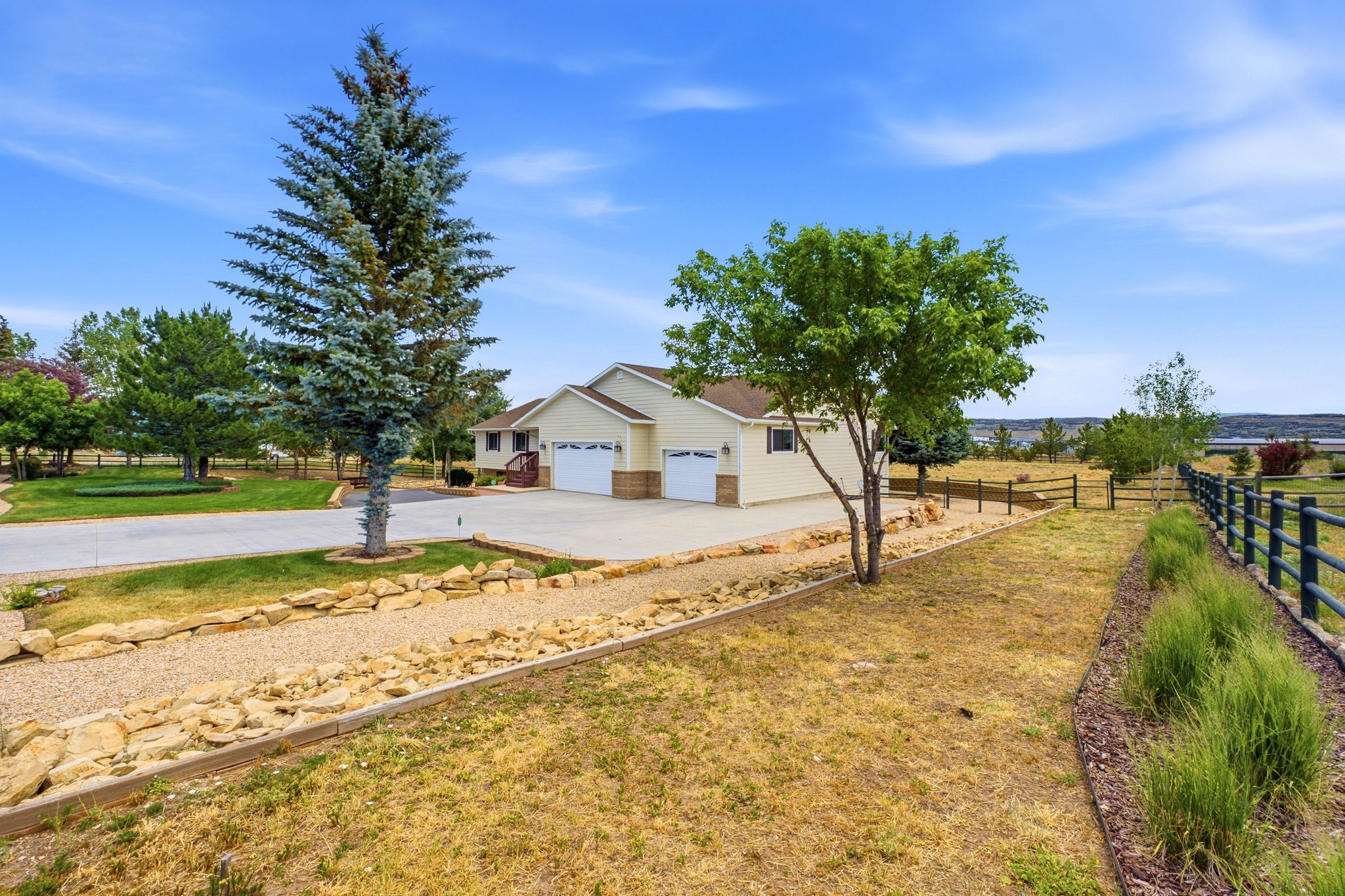 Ranch-style exterior with an attached two-car garage, concrete driveway, and mature landscaping