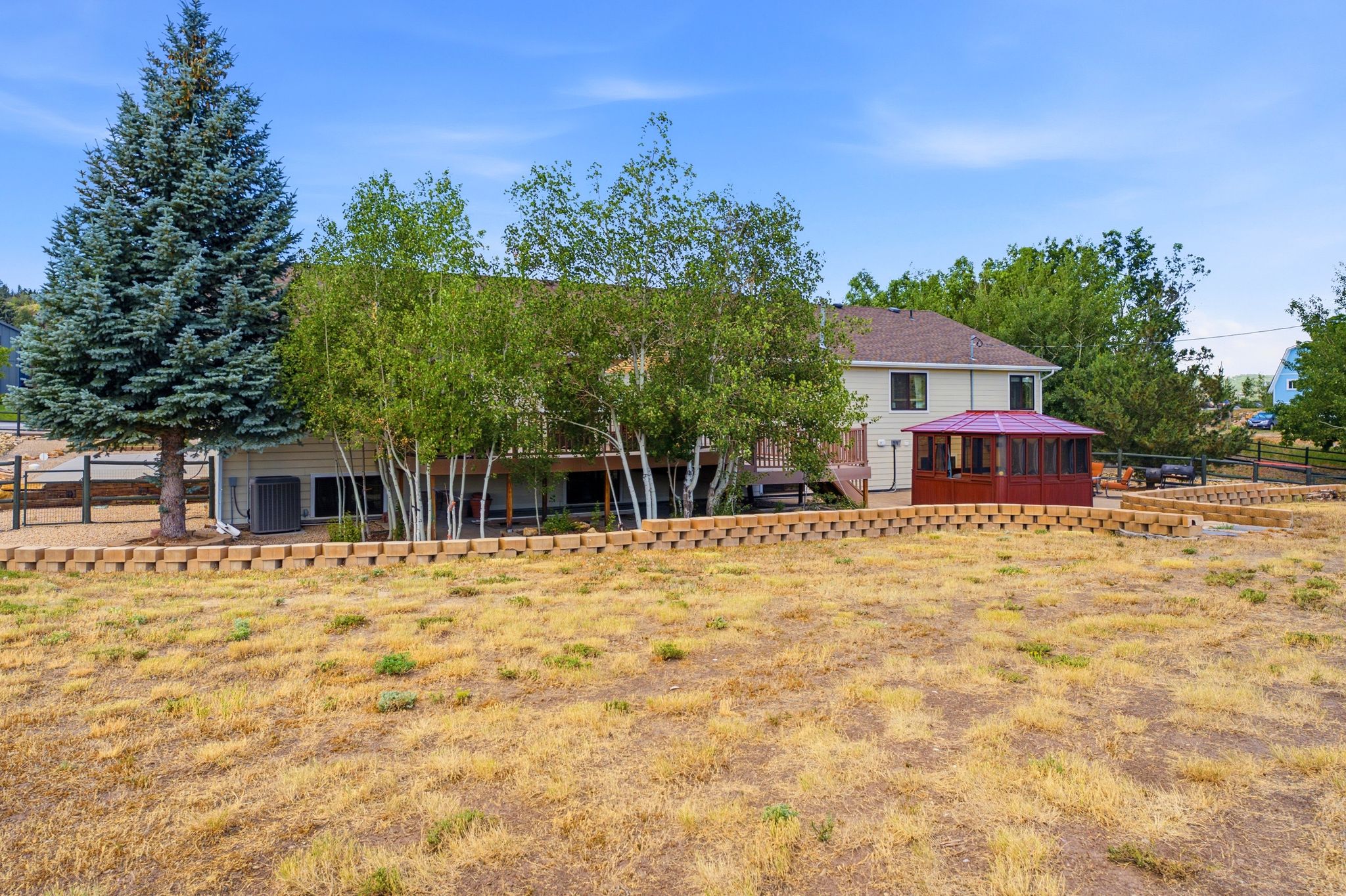 Expansive terraced yard featuring a large retaining wall system and a red-roofed gazebo