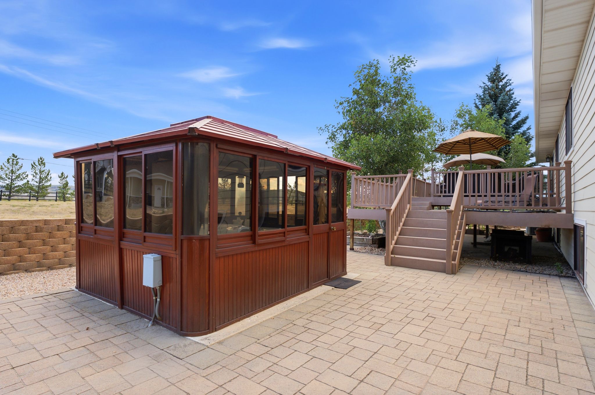 Spacious outdoor living area featuring a screened gazebo, multi-level composite deck with steps, and a paver patio