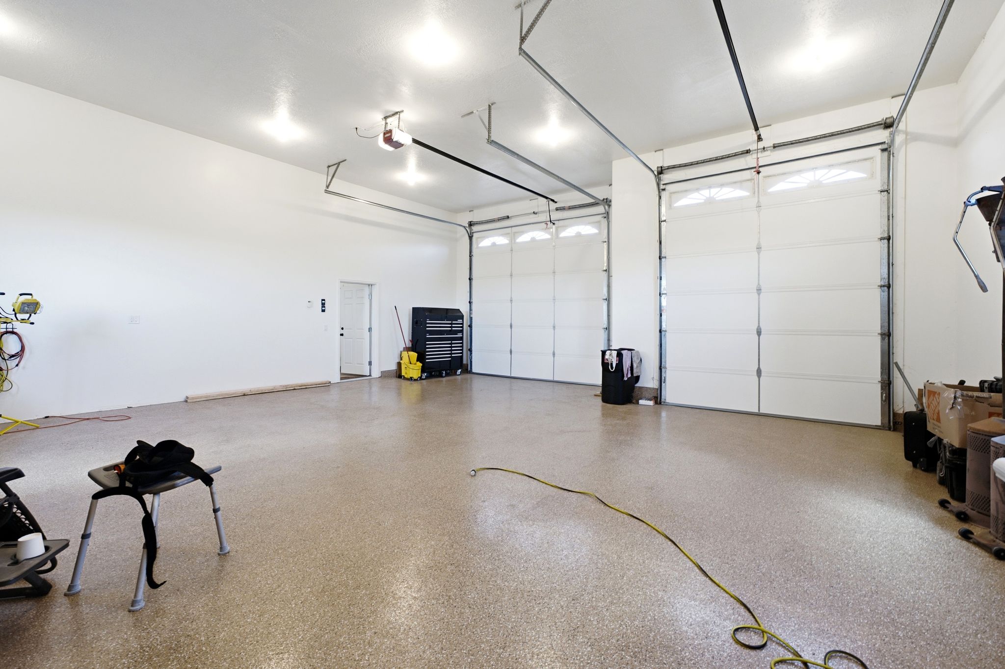 Expansive garage featuring two overhead doors, a finished epoxy floor, and recessed ceiling lighting