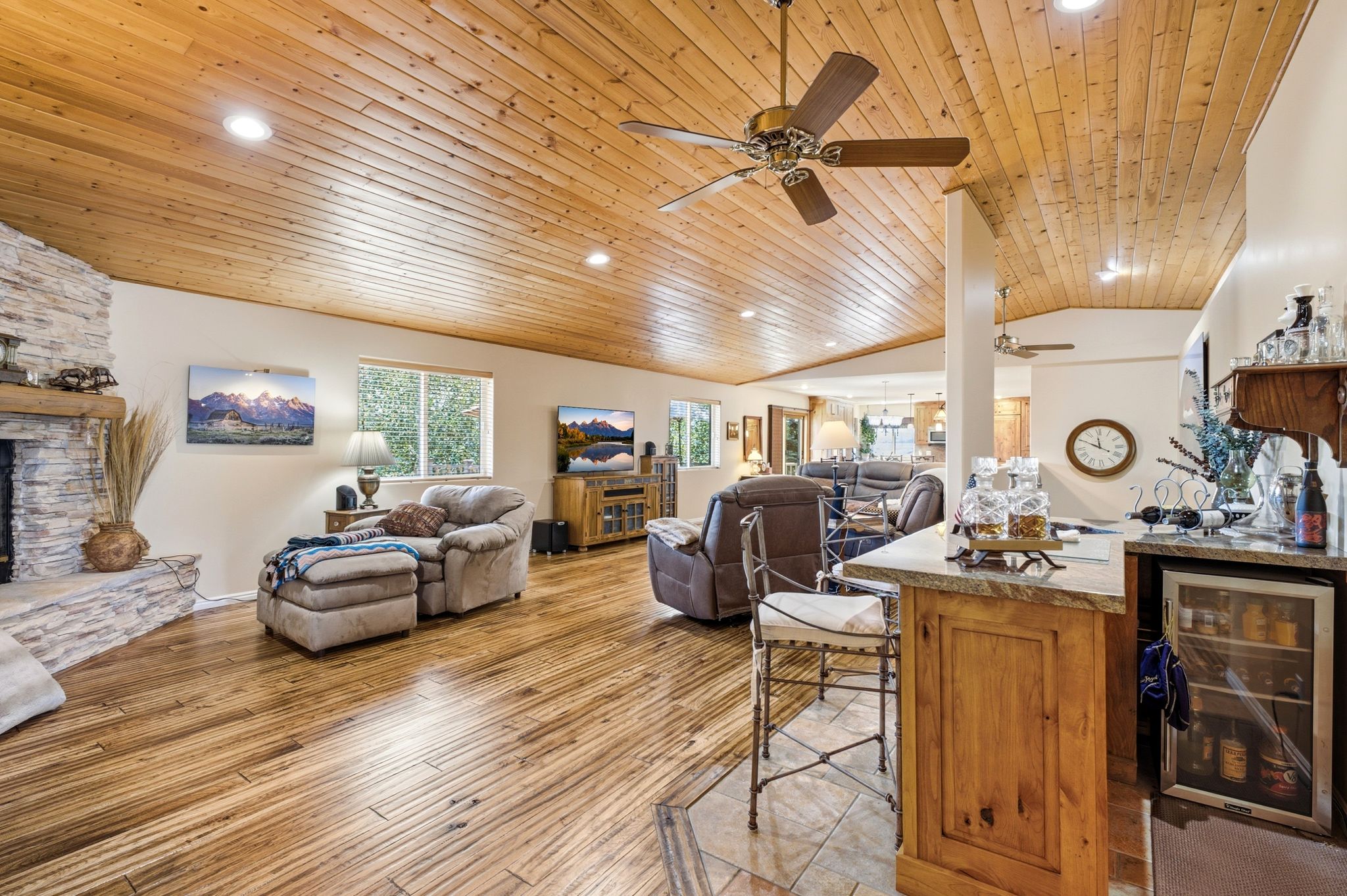 Spacious interior featuring wood-finish flooring, a stone-clad fireplace, and a wood-paneled ceiling with recessed lighting