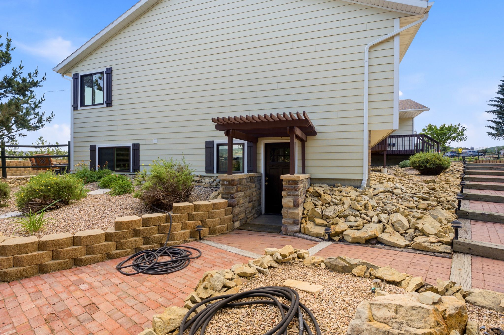 Walk-out lower level entry featuring a wood pergola and stone column accents