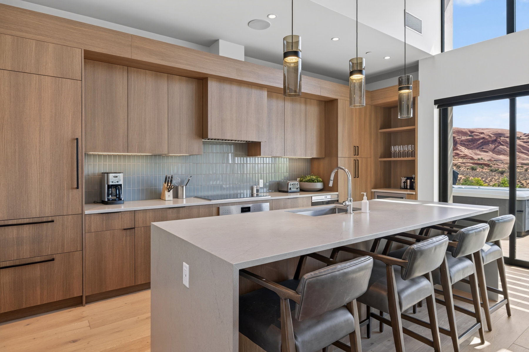 Modern kitchen featuring light wood-finish cabinetry, a large center island with integrated sink, and a tiled backsplash