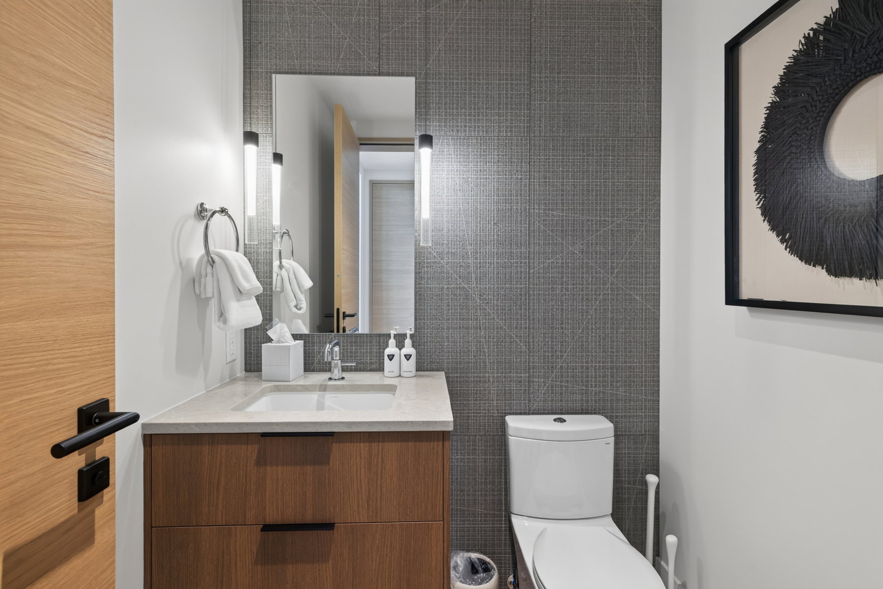Modern bathroom featuring a wood-finish vanity with a light-toned countertop, rectangular undermount sink, and polished chrome faucet
