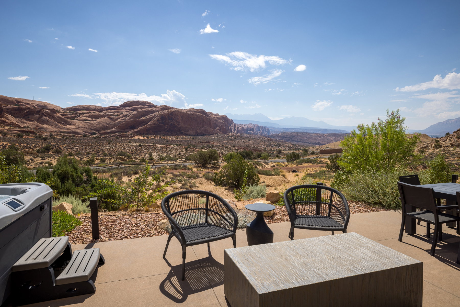 Spacious outdoor patio with a hot tub, concrete paving, and a distant mountain backdrop