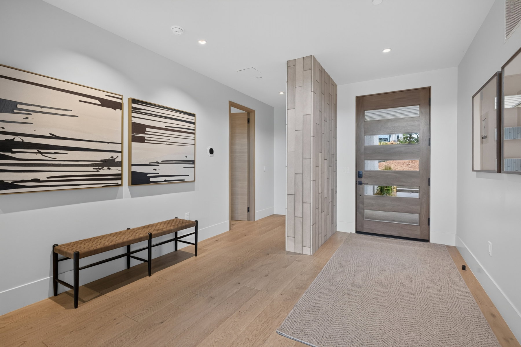 Modern entryway featuring a light wood-finish door with multiple glass panels